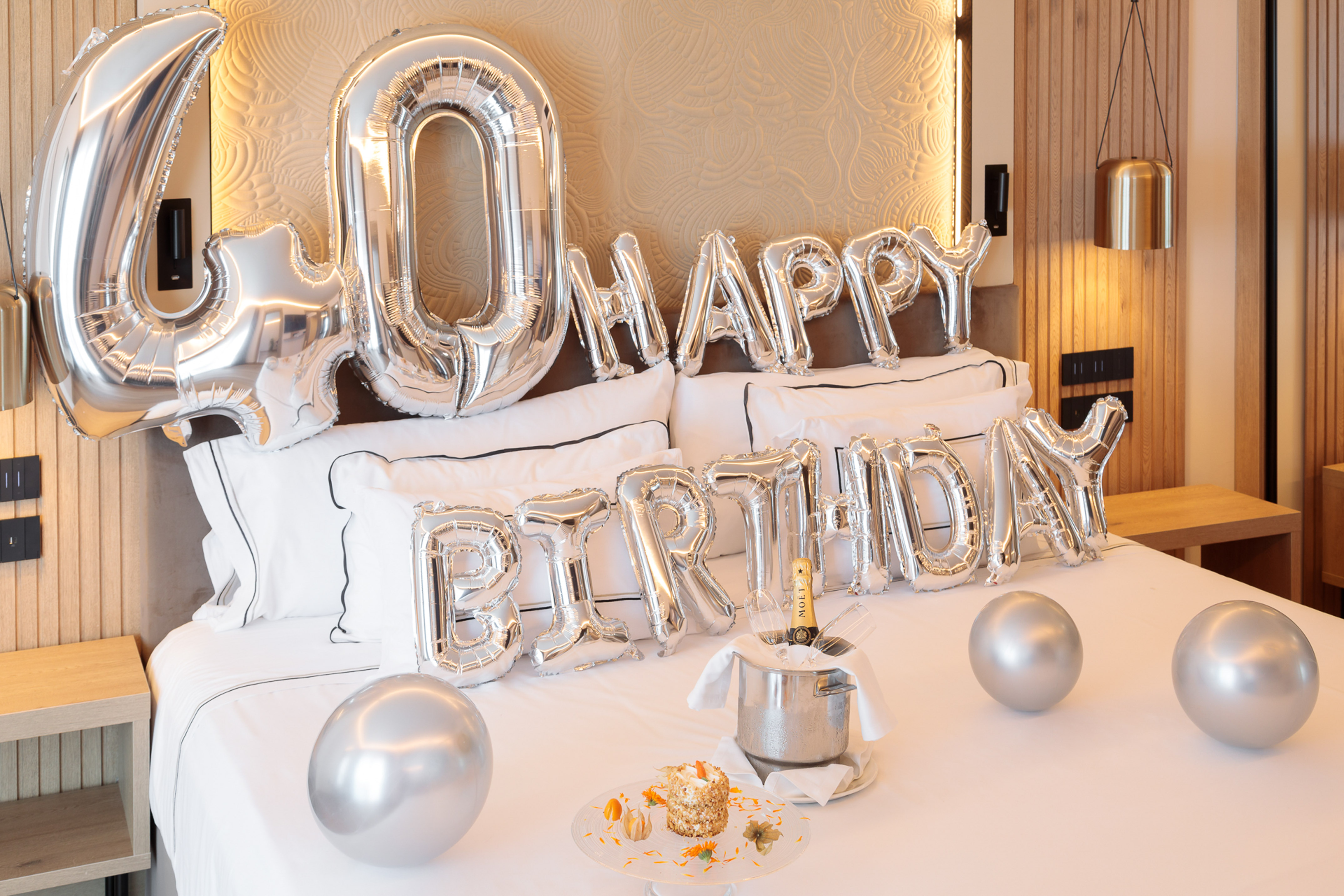 a bed with balloons and a champagne bucket
