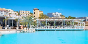 a pool with a white structure and palm trees