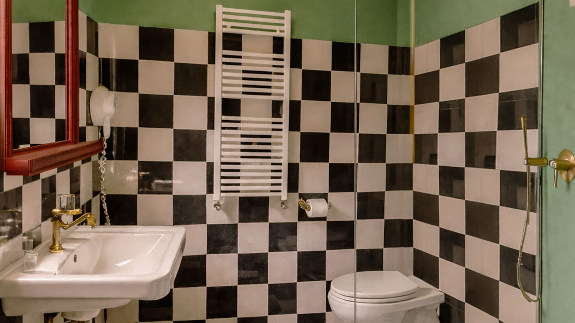 Green and black-white checkered bathroom, white sink, toilet, glass shower.
