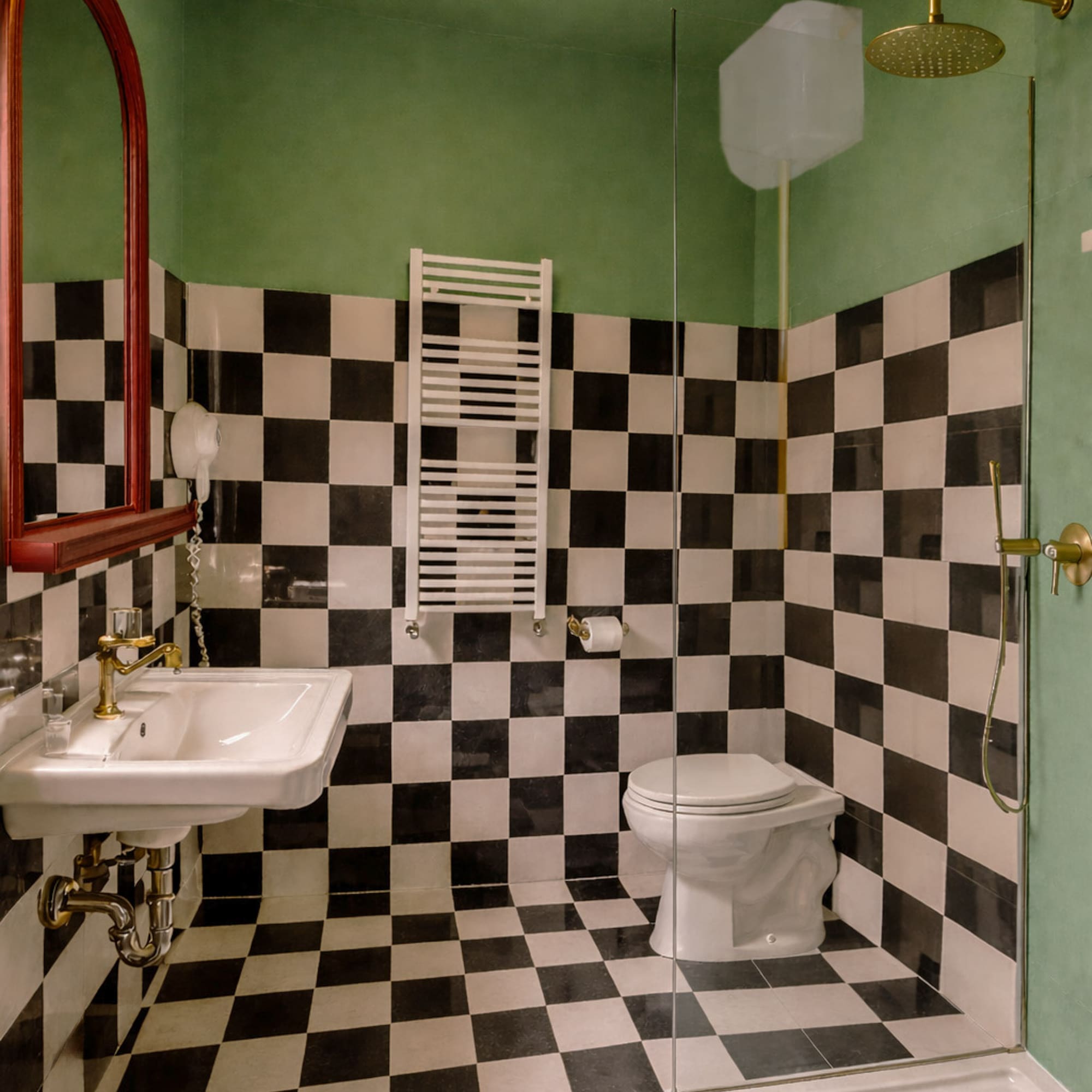 Green bathroom with black and white checkered tiles, sink, toilet, shower.