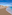 a beach with buildings and blue water