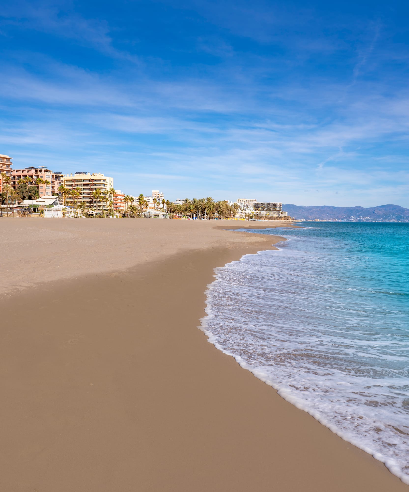 a beach with buildings and blue water