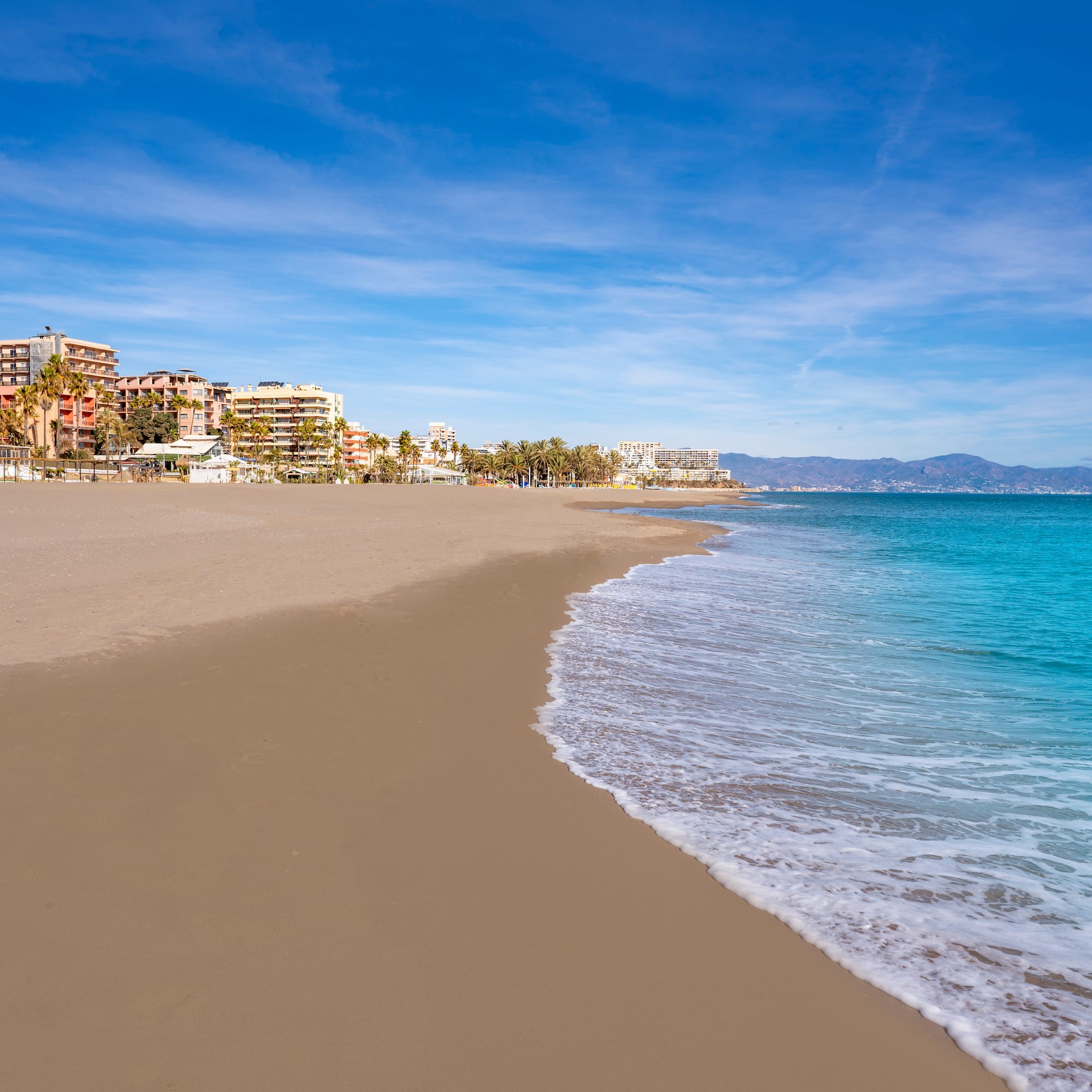 a beach with buildings and blue water