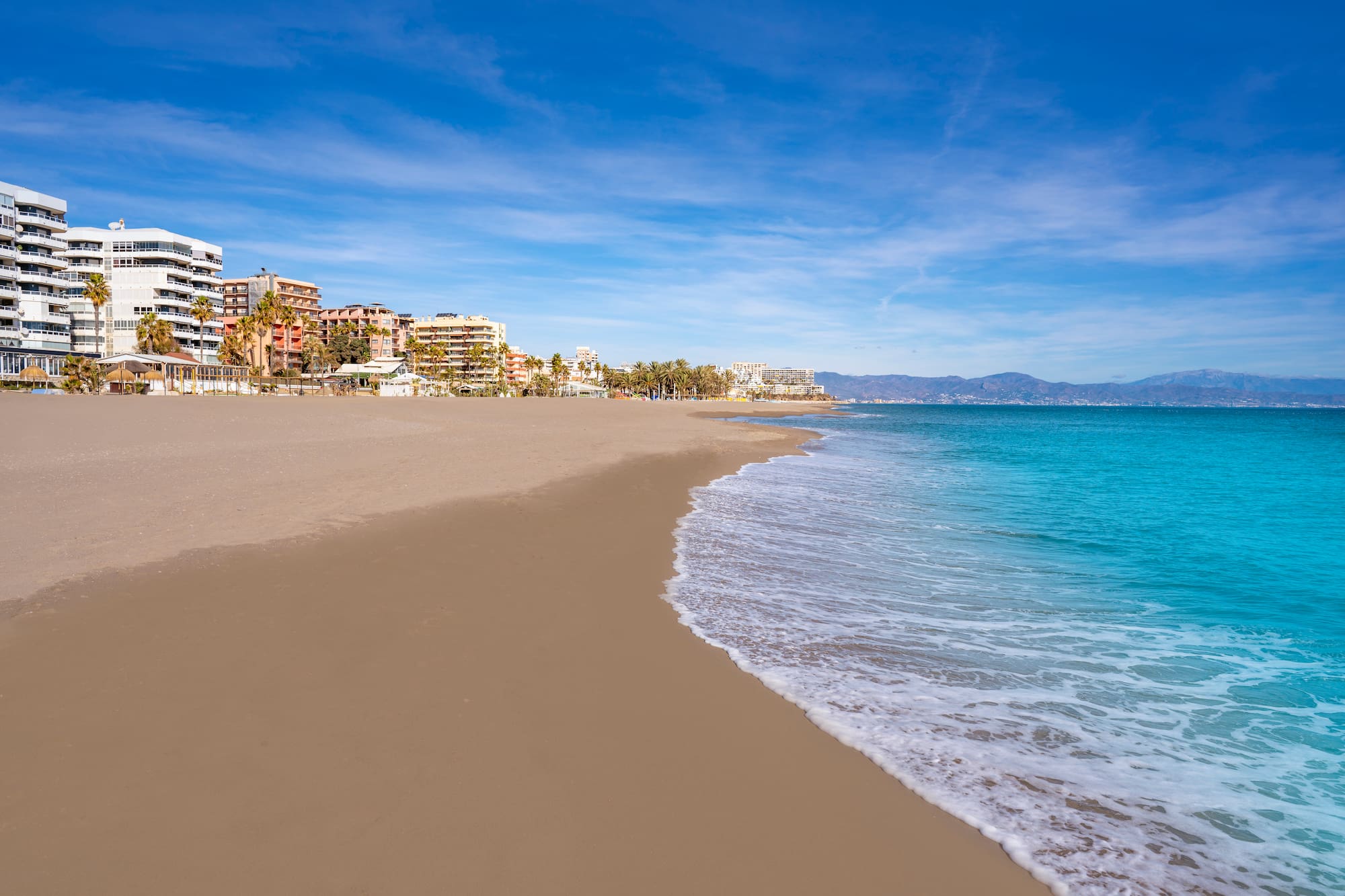 a beach with buildings and blue water