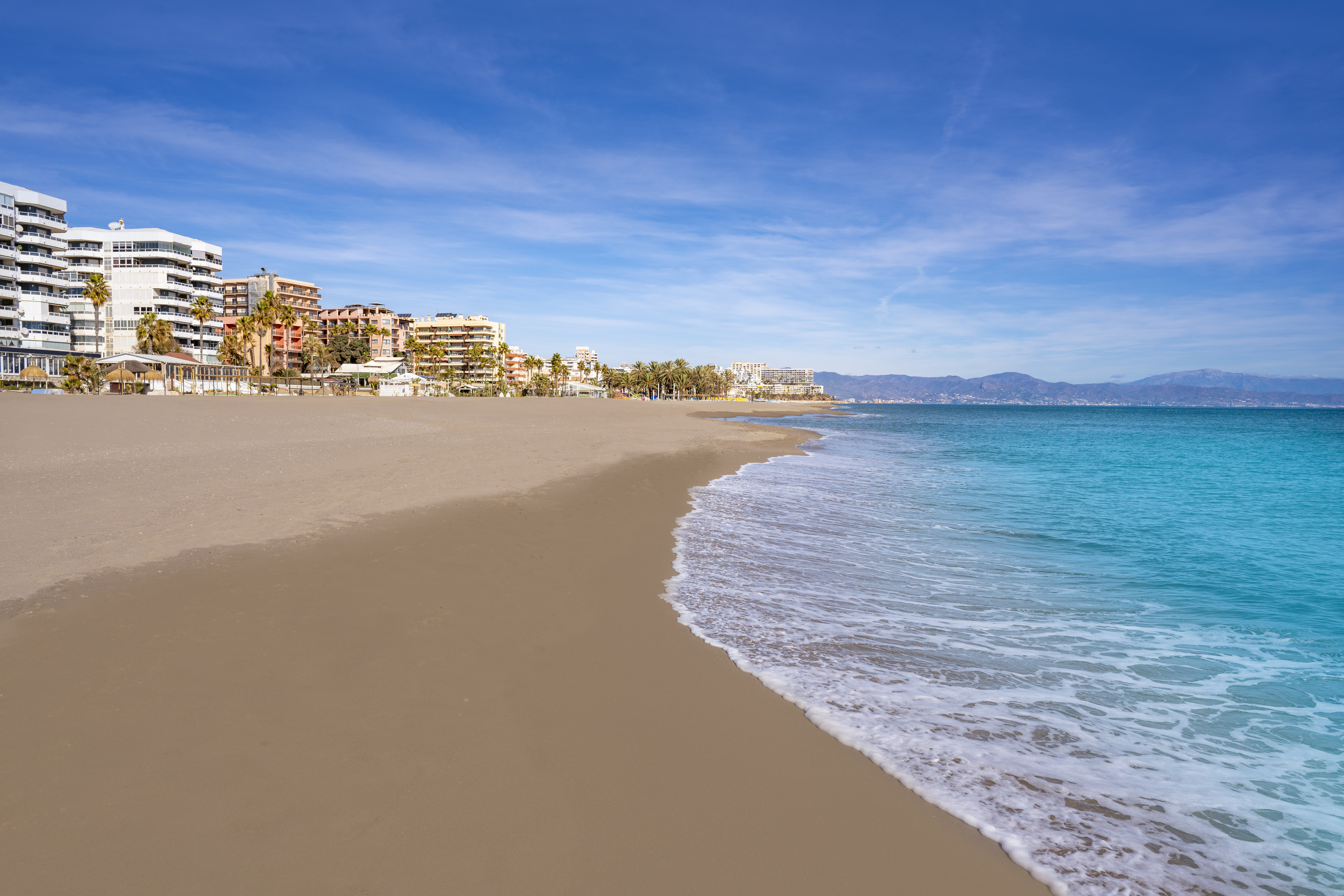a beach with buildings and blue water