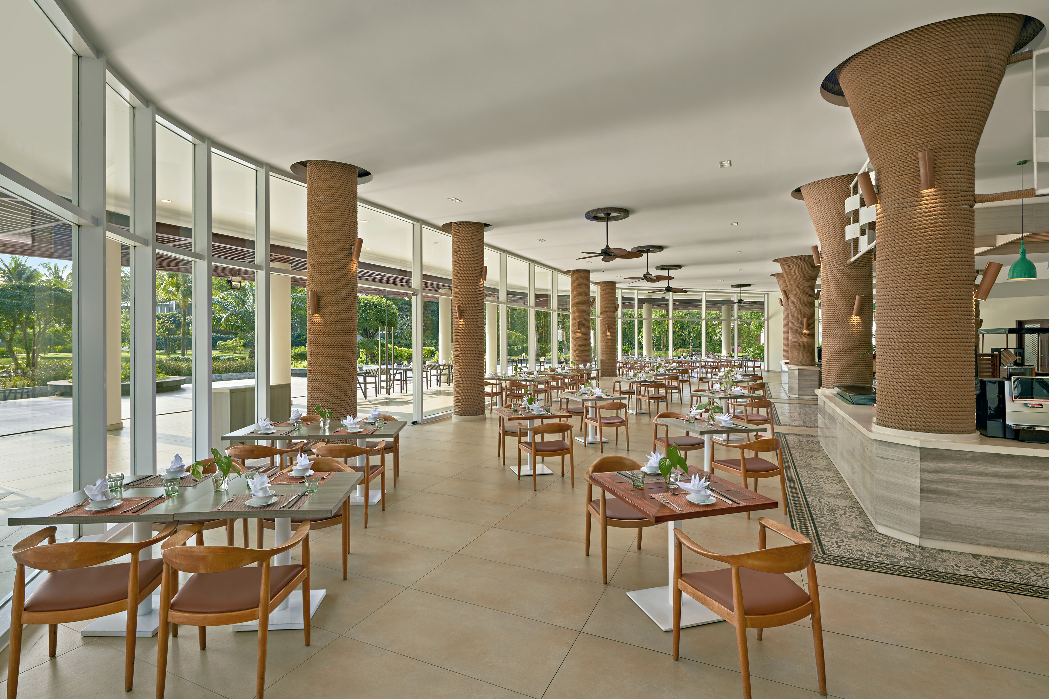 Resort restaurant with set tables, rope columns, and garden views.