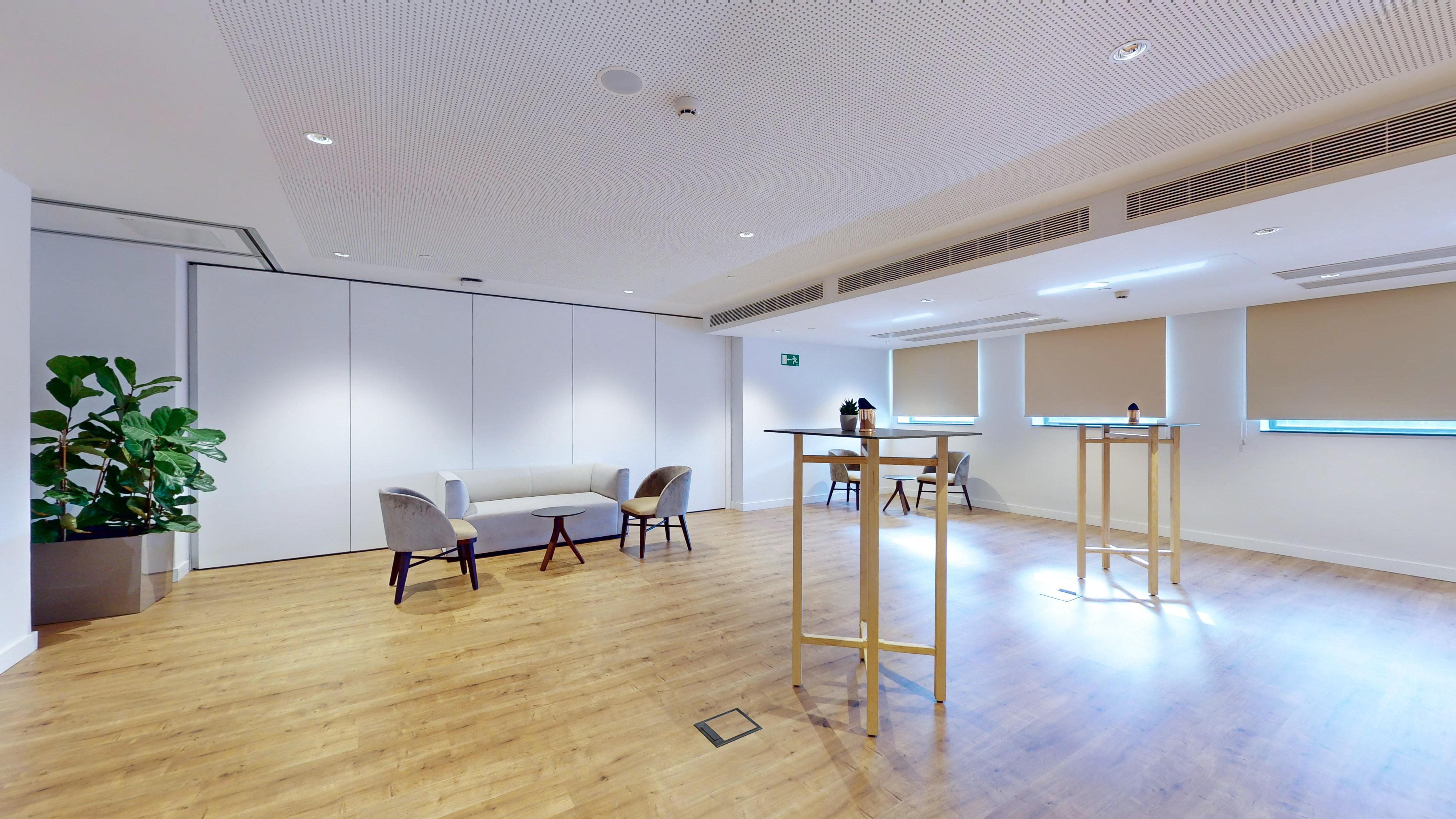Modern event space with lounge seating, cocktail tables, and wooden floor.