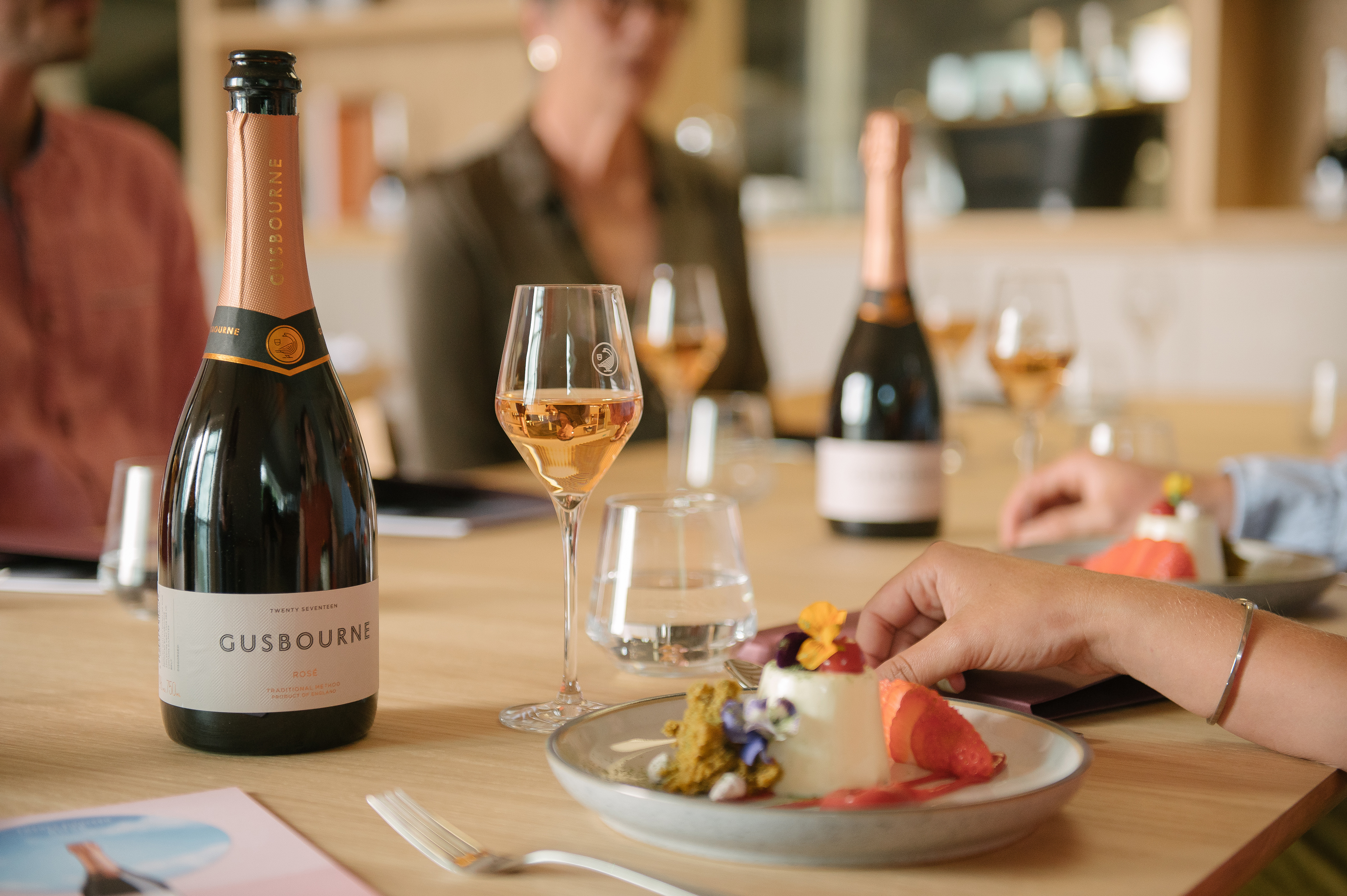 a person's hand on a plate of food and a bottle of wine