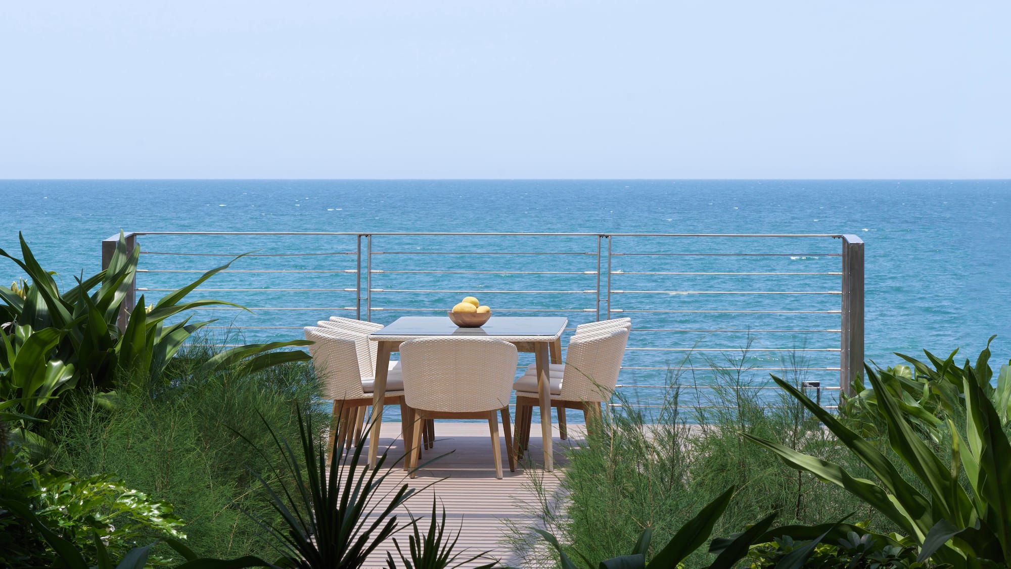 a table and chairs on a deck overlooking the ocean