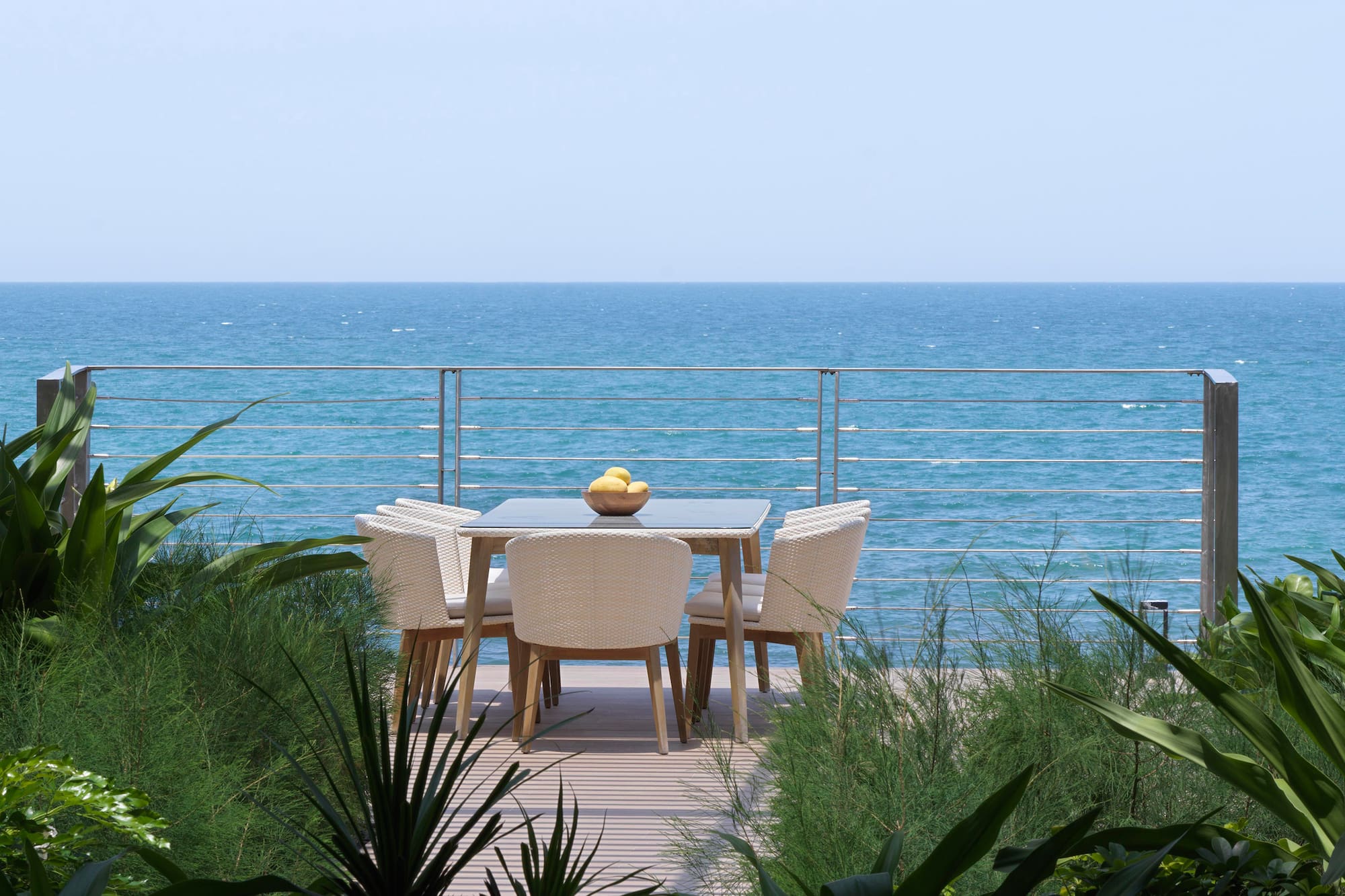 a table and chairs on a deck overlooking the ocean
