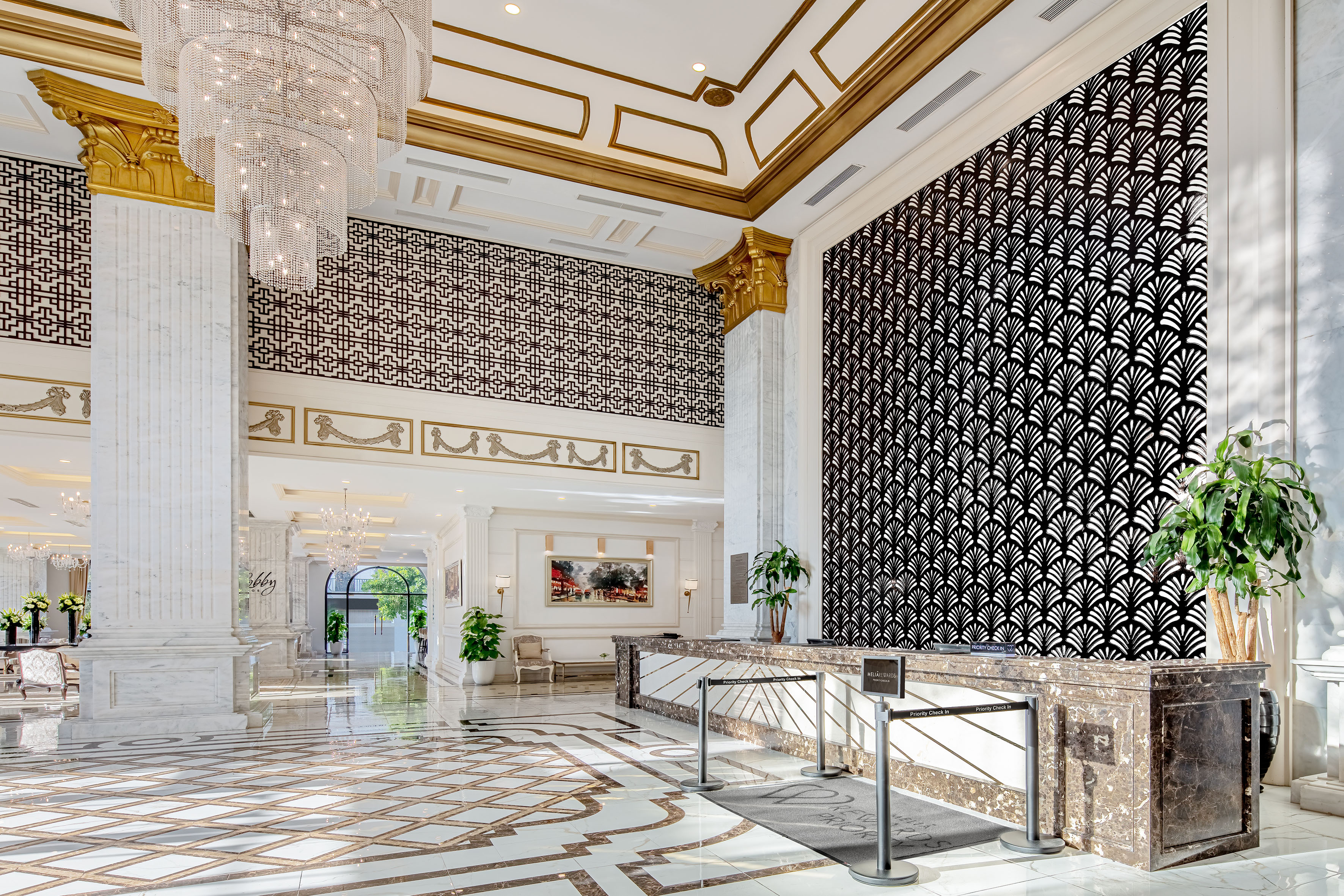 Grand hotel lobby with crystal chandelier, marble, and Art Deco patterns.