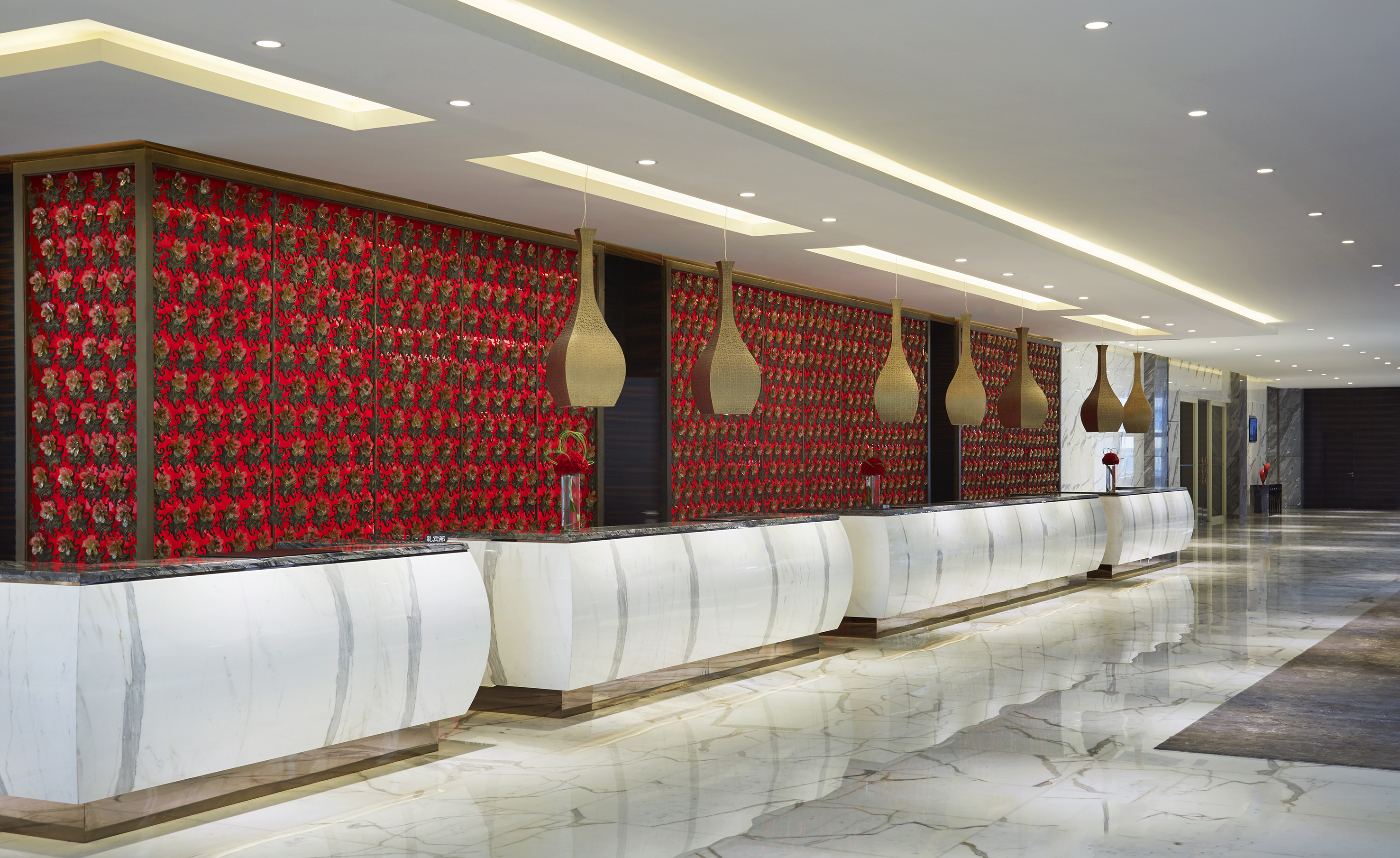 Hotel reception: marble counters, red floral wall, modern pendant lights.