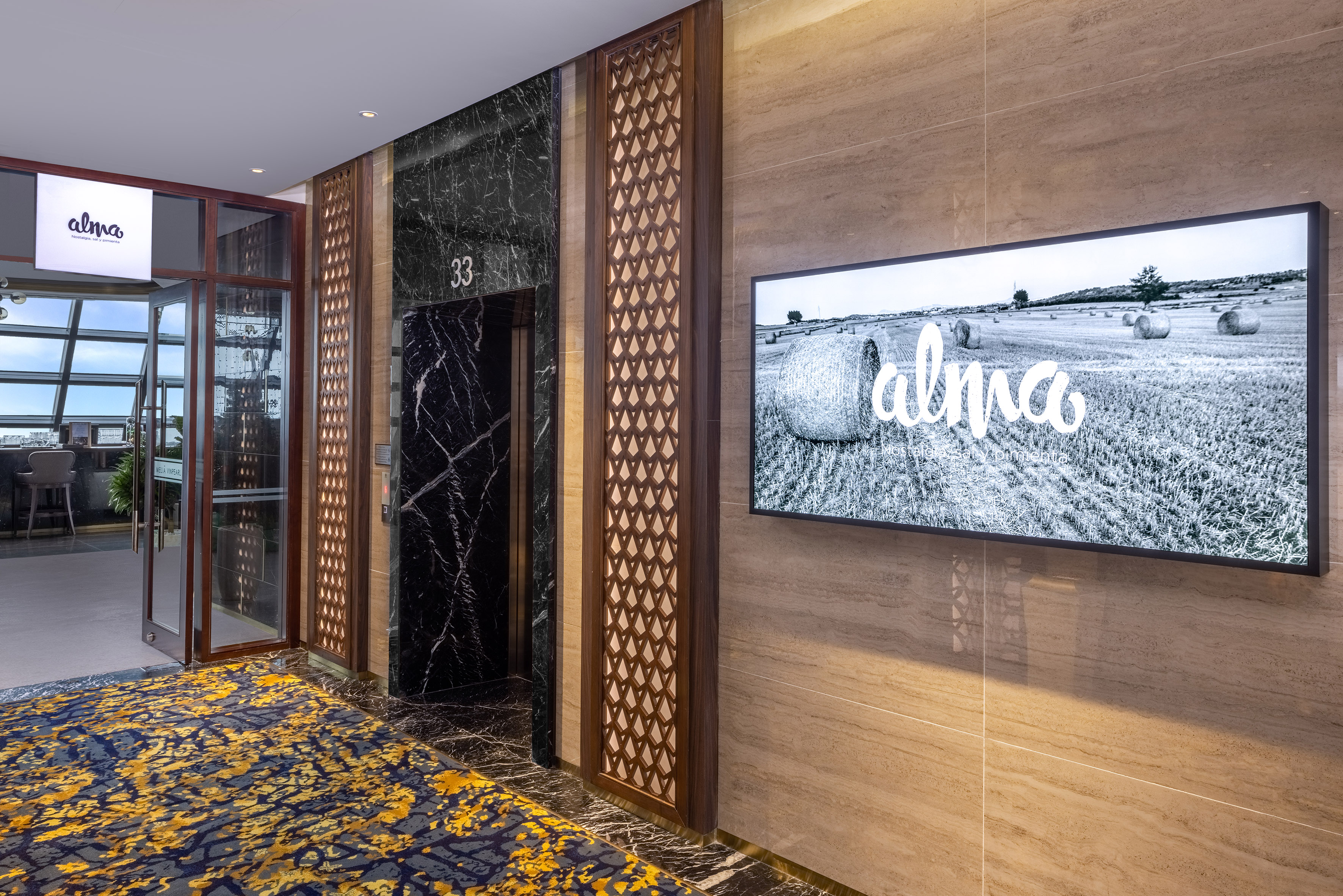 Alma hotel restaurant entrance lobby, elevator, and digital display.