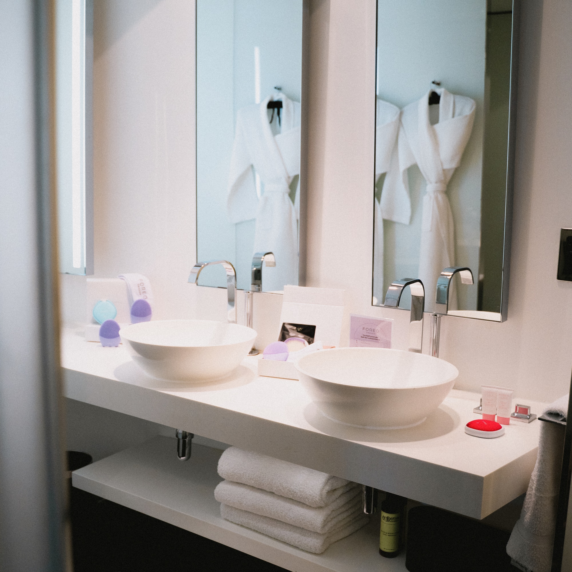 Hotel bathroom double vanity with white sinks, chrome faucets, and mirrors.