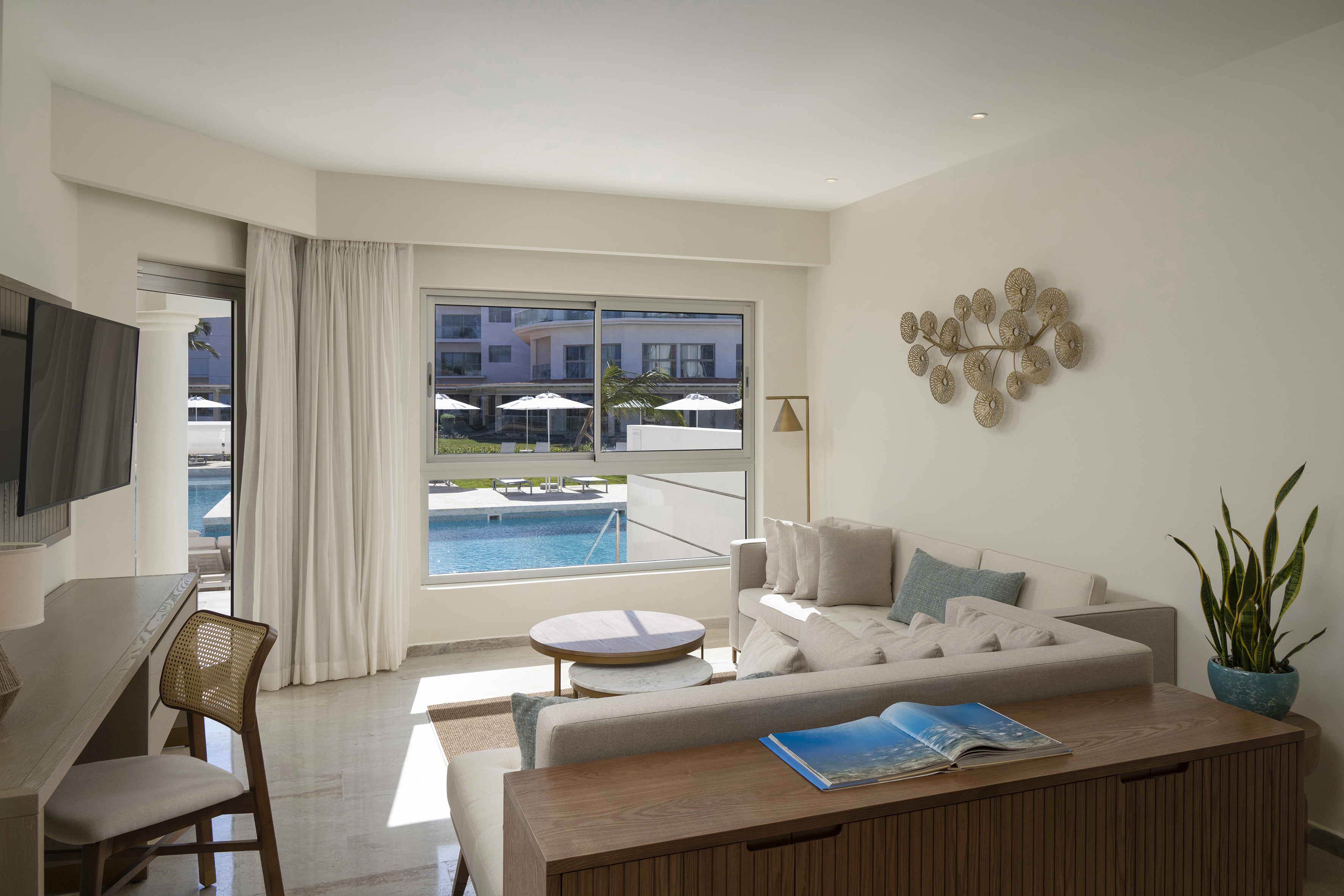 Modern hotel suite living room featuring a pool view, sofa, and stylish decor.