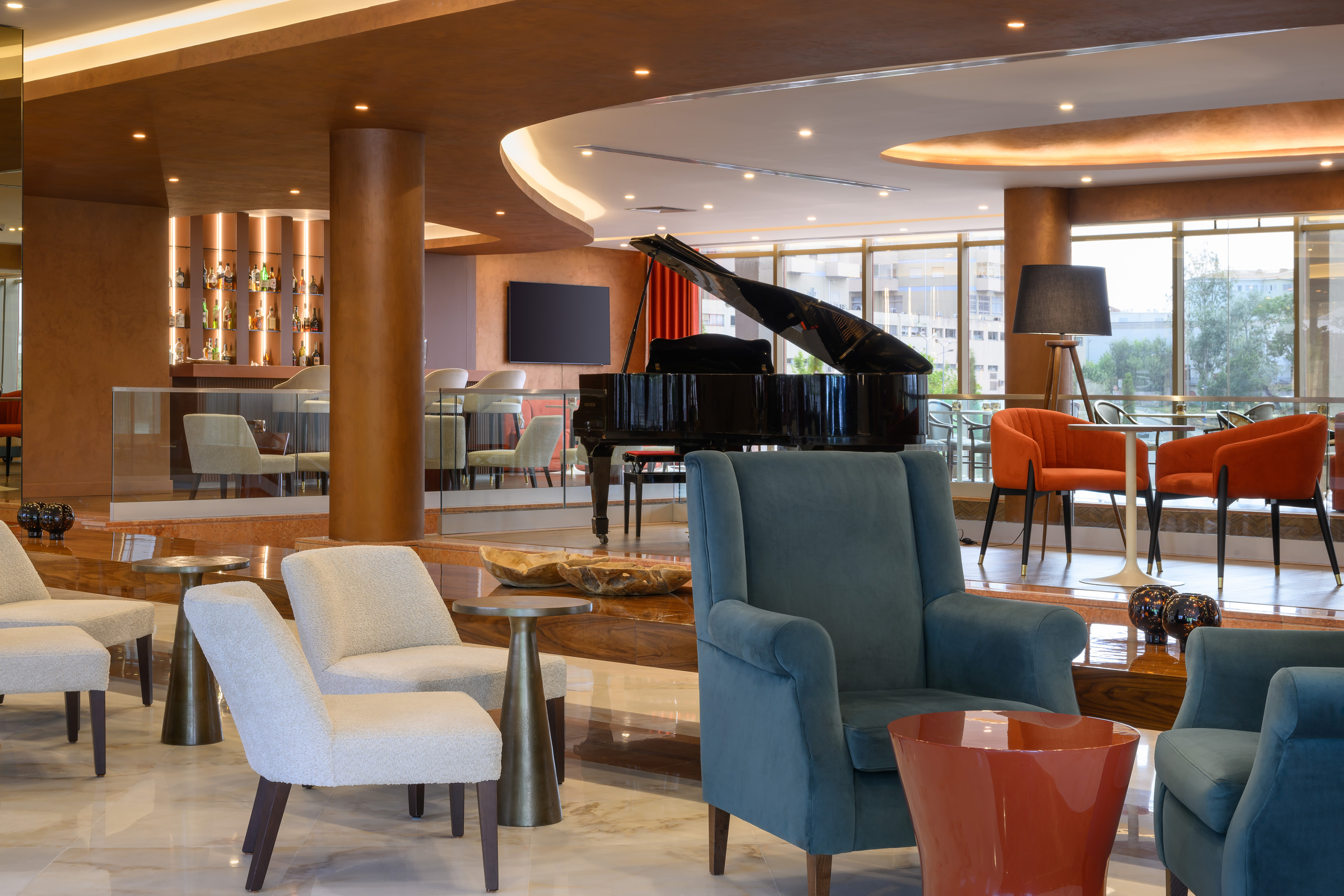 Elegant hotel lounge with grand piano, bar, and modern armchairs.