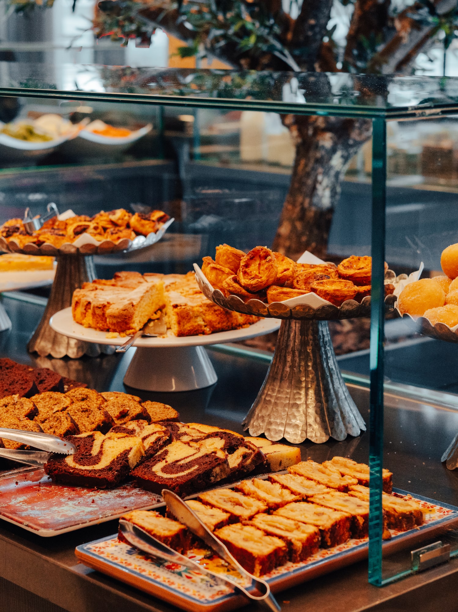 Hand choosing cake at hotel breakfast buffet with various pastries & desserts.