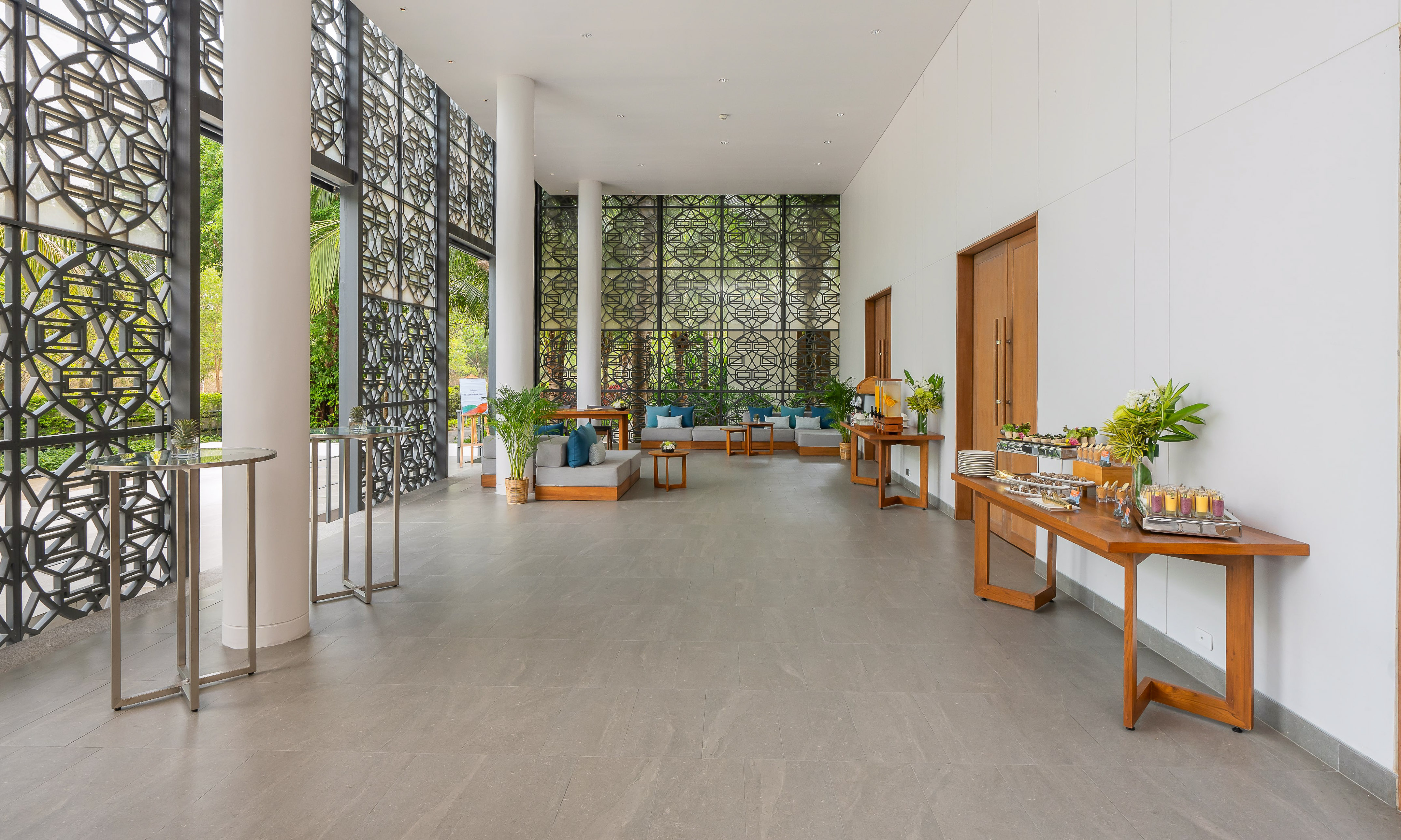 Modern resort lobby with patterned screens, lounge seating, and buffet tables.
