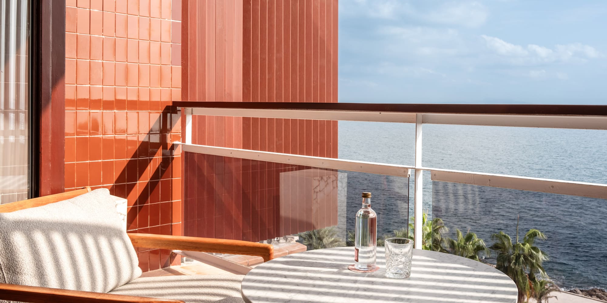a chair and a table on a balcony overlooking the ocean