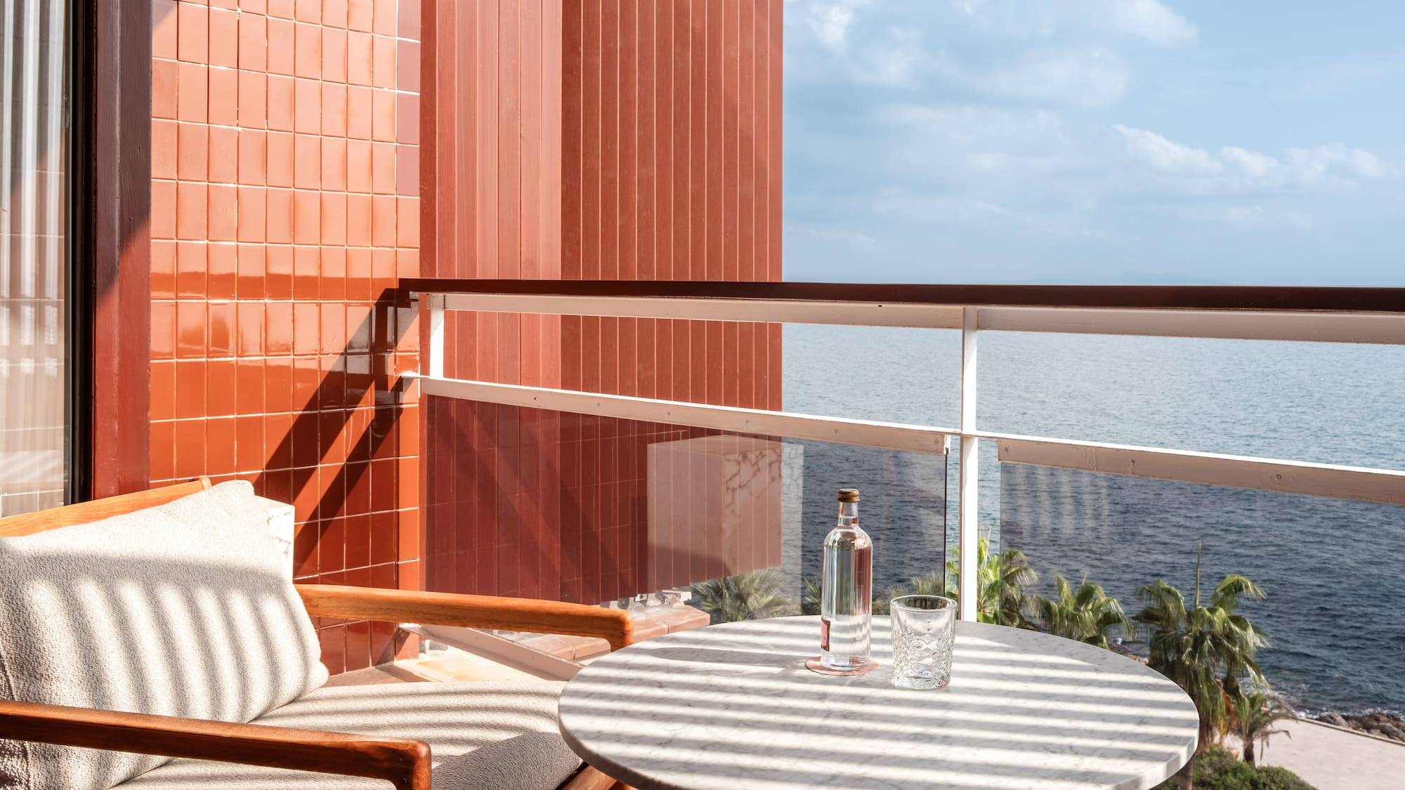 a chair and a table on a balcony overlooking the ocean