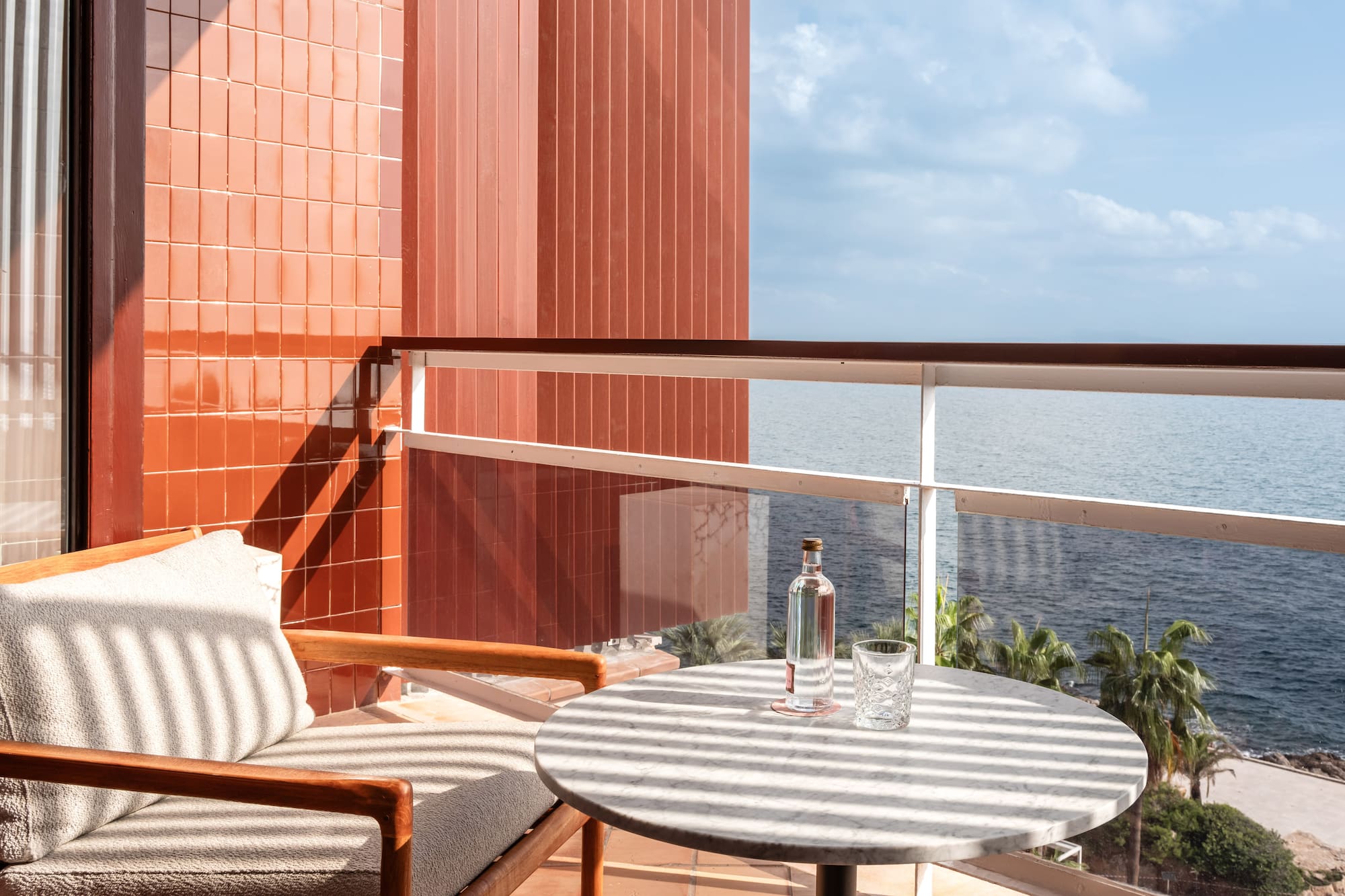 a chair and a table on a balcony overlooking the ocean