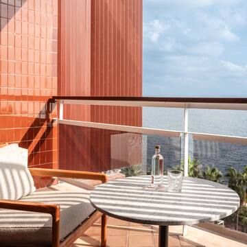 a chair and a table on a balcony overlooking the ocean