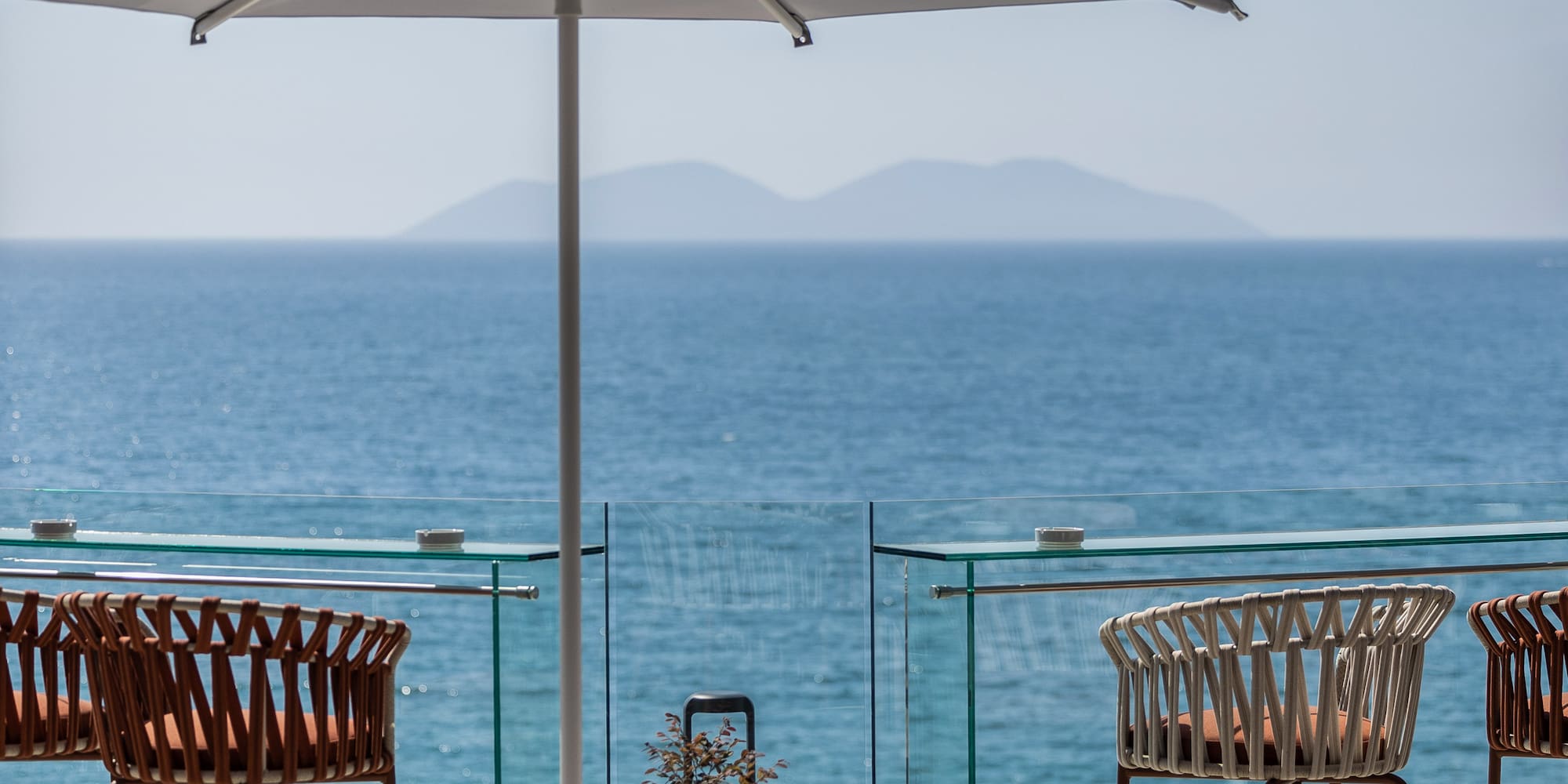 a patio with chairs and umbrellas and a view of the ocean