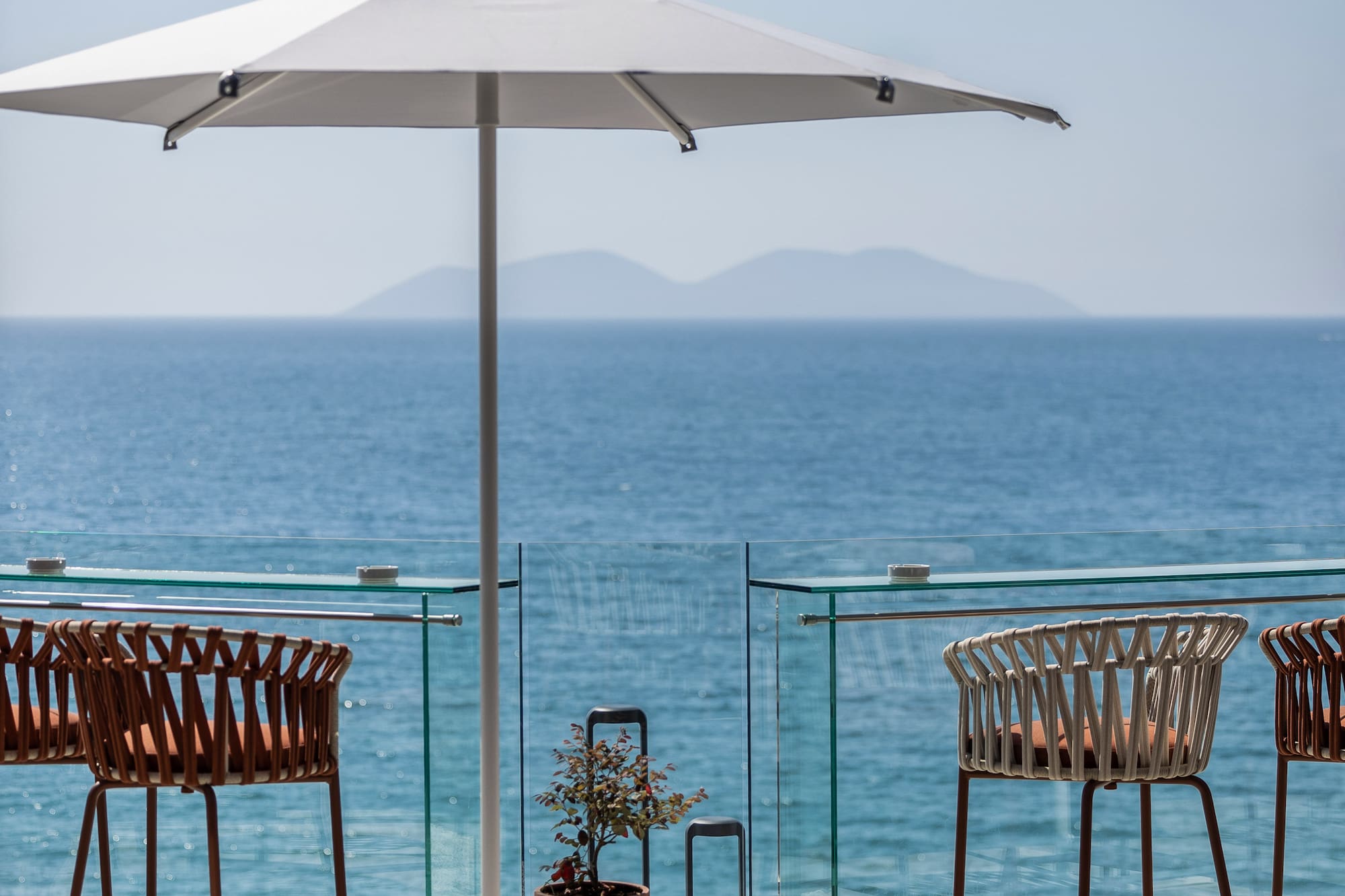 a patio with chairs and umbrellas and a view of the ocean