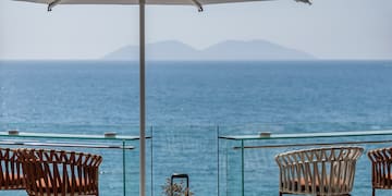 a patio with chairs and umbrellas and a view of the ocean