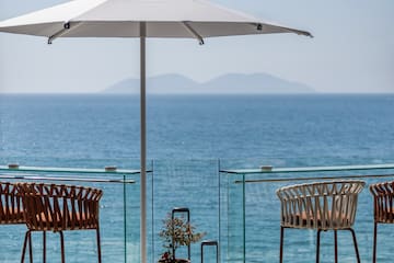 a patio with chairs and umbrellas and a view of the ocean