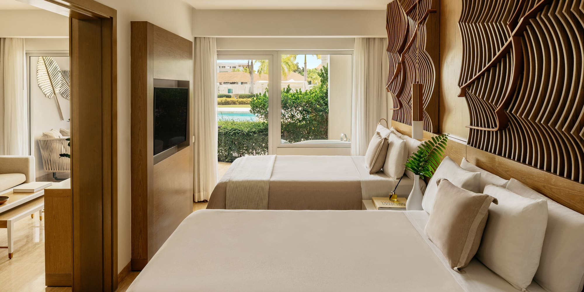 Stylish resort bedroom with two beds, pool view window, and textured wood art.