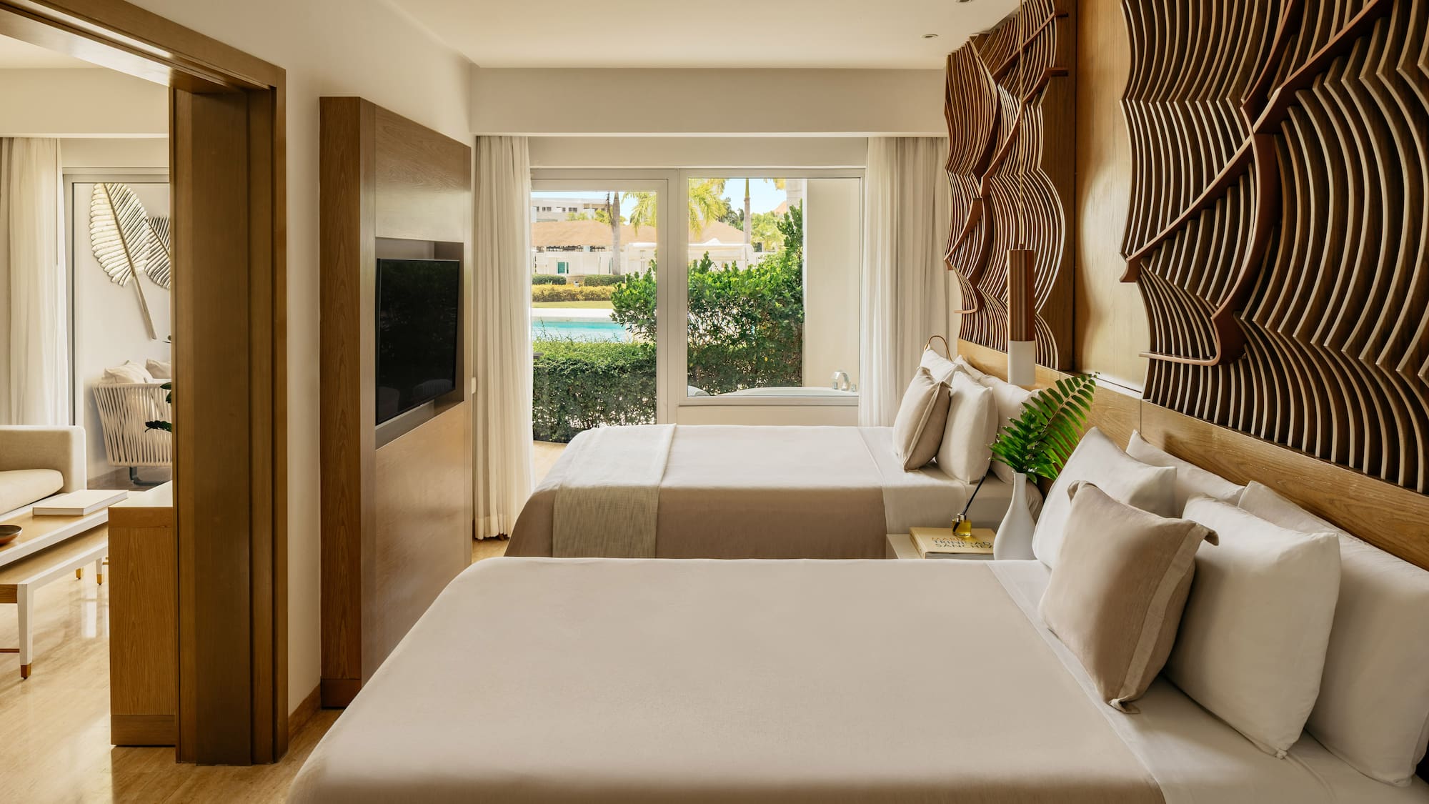 Stylish resort bedroom with two beds, pool view window, and textured wood art.