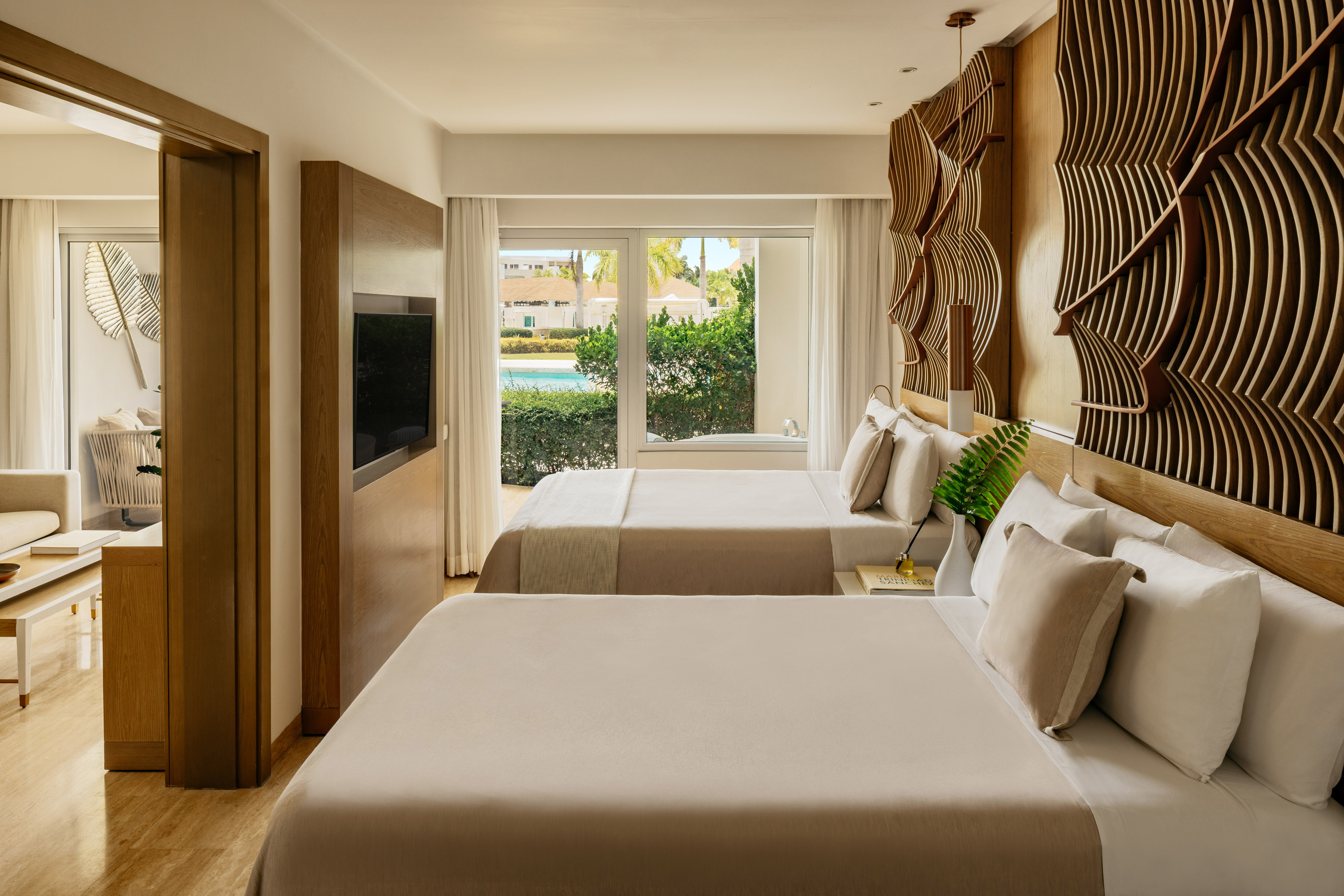 Stylish resort bedroom with two beds, pool view window, and textured wood art.