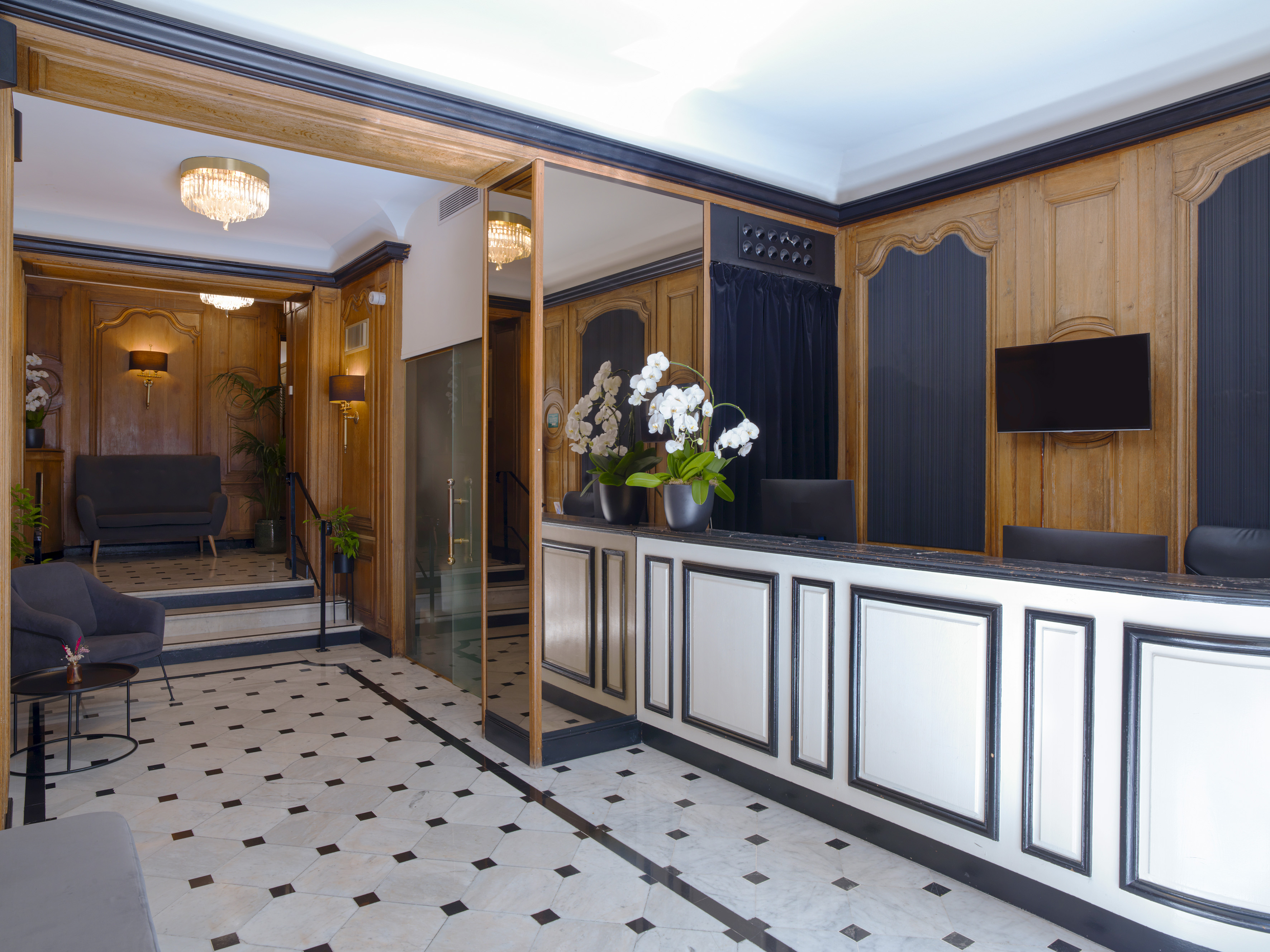 Elegant hotel lobby reception with dark wood paneling, marble floor, and white desk.