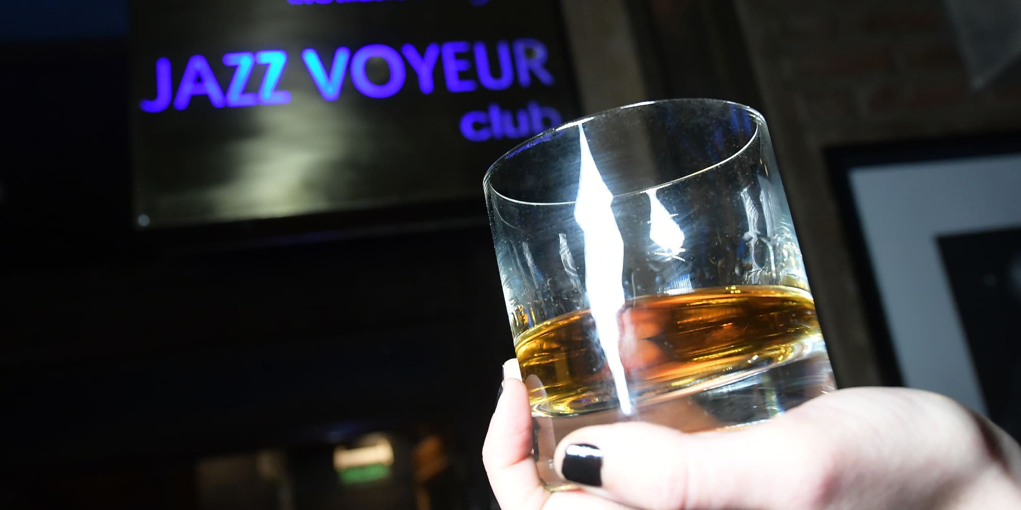 a hand holding a glass of liquid