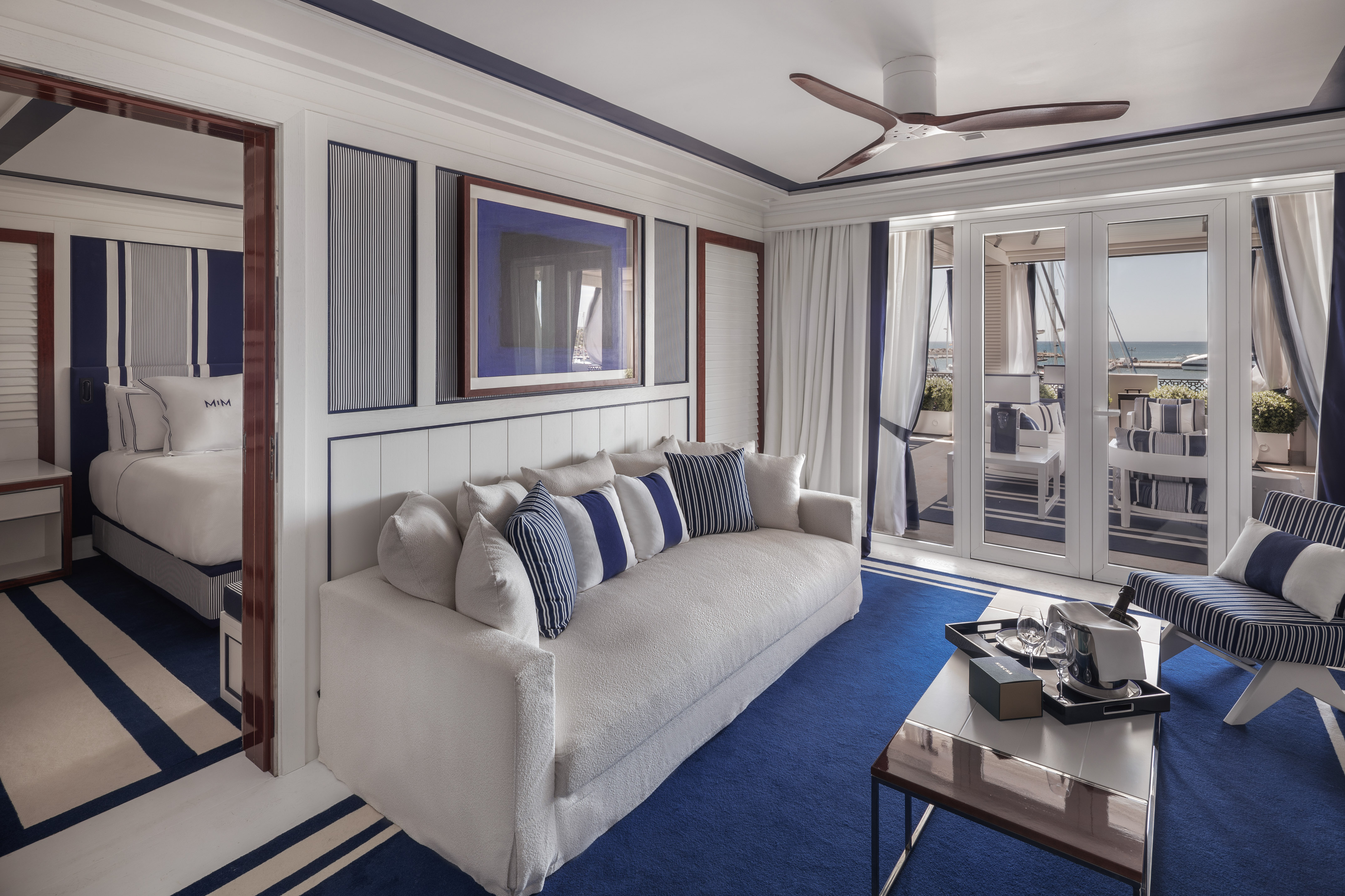 Nautical luxury suite: blue/white decor, marina view, elegant living area.