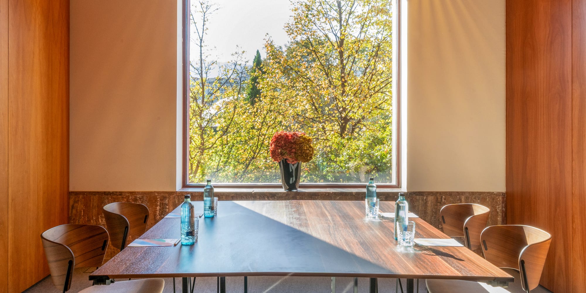 a table with chairs and a vase of flowers in front of a window