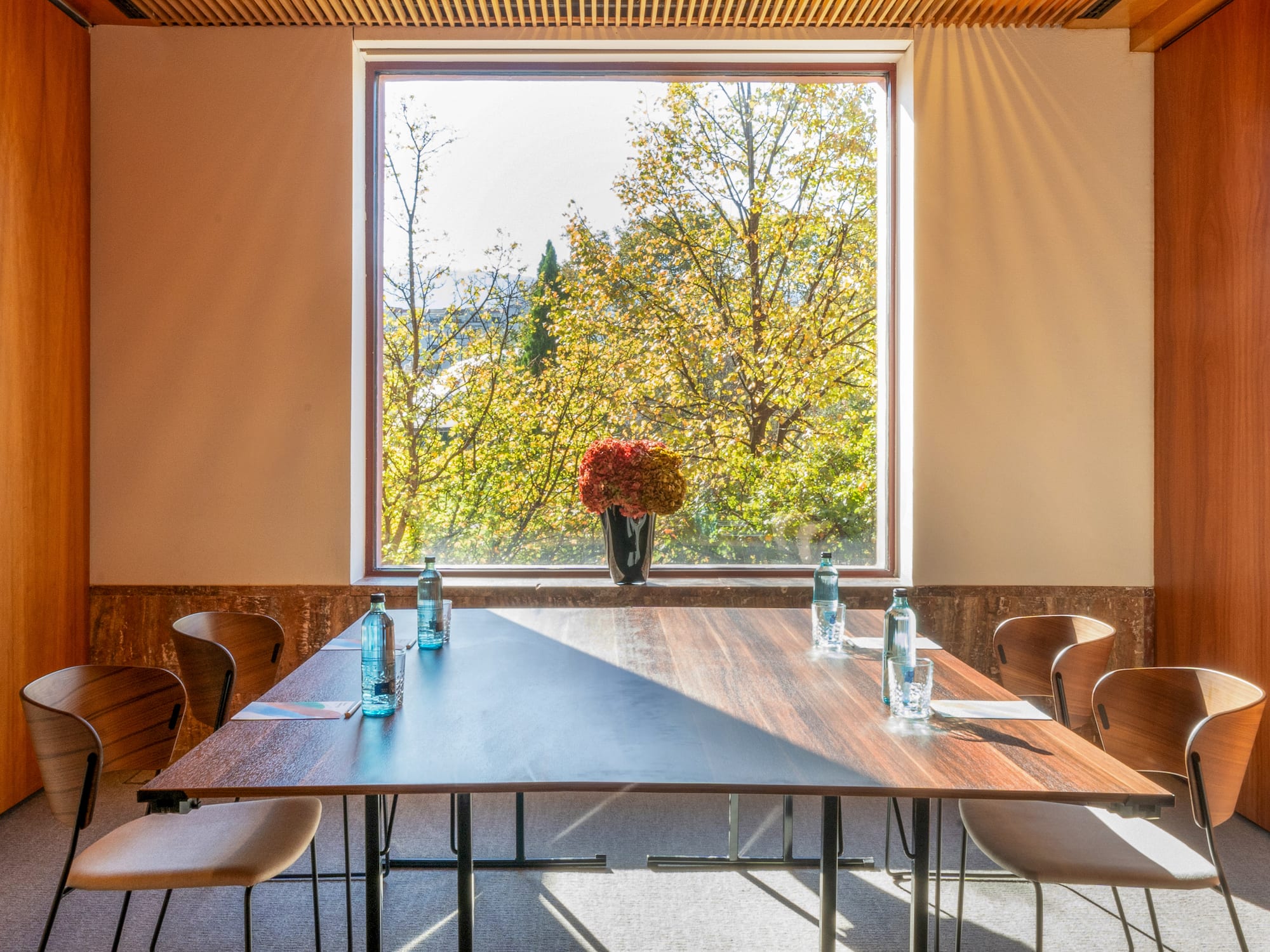 a table with chairs and a vase of flowers in front of a window