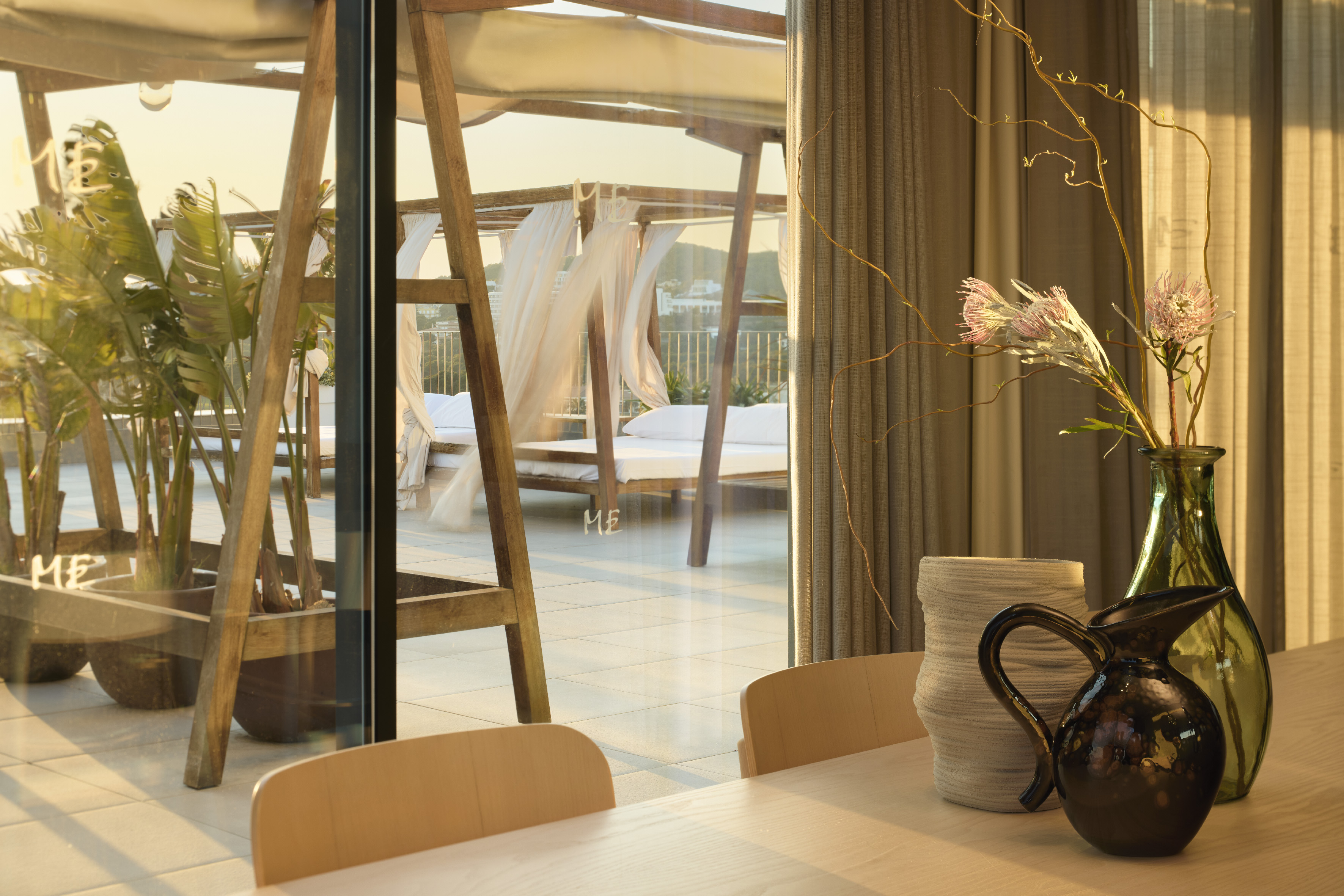 Dining table with floral decor, sunny luxury terrace view with canopy daybeds.