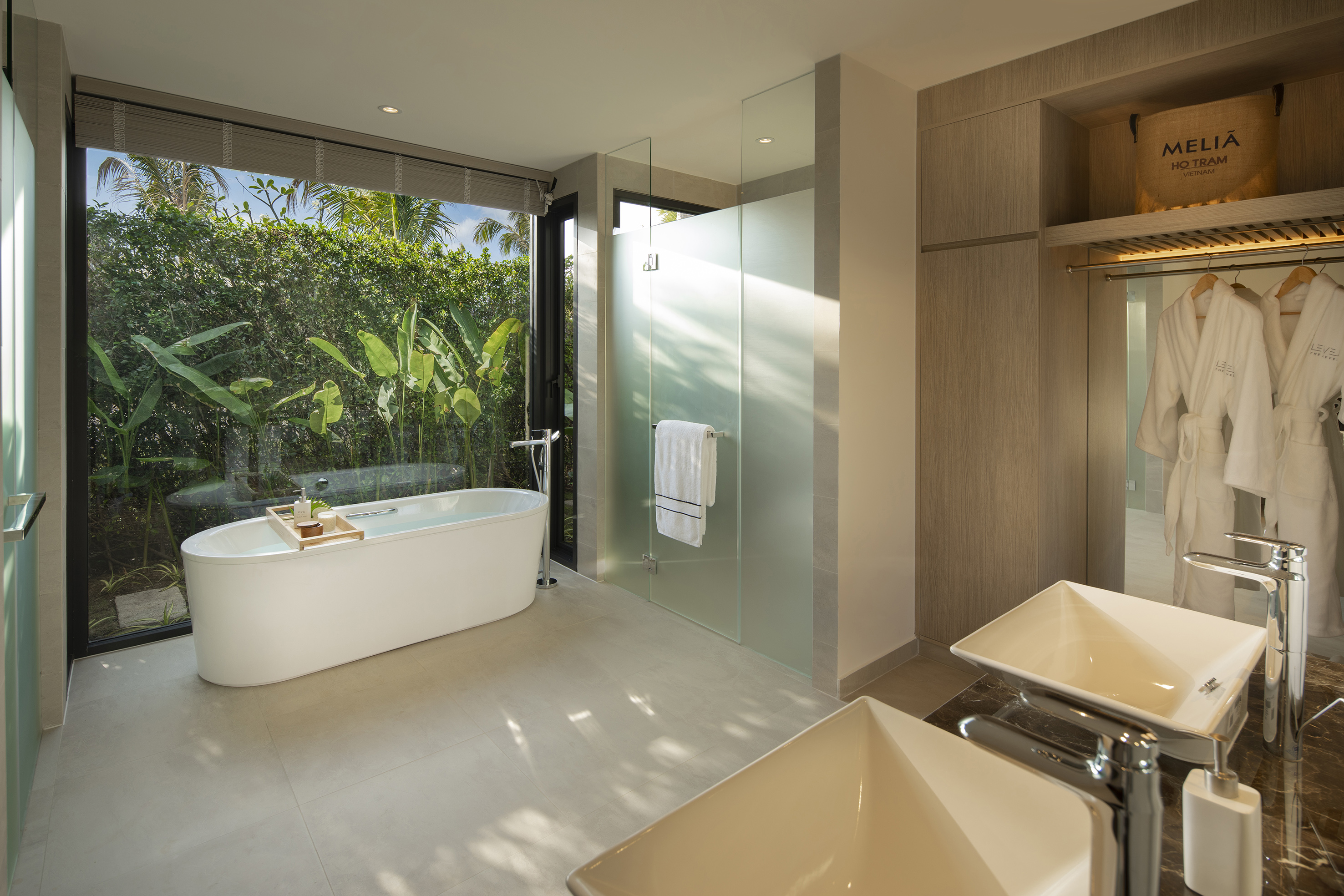 Luxury Meliá Ho Tram bathroom with freestanding tub, tropical view, double vanity.