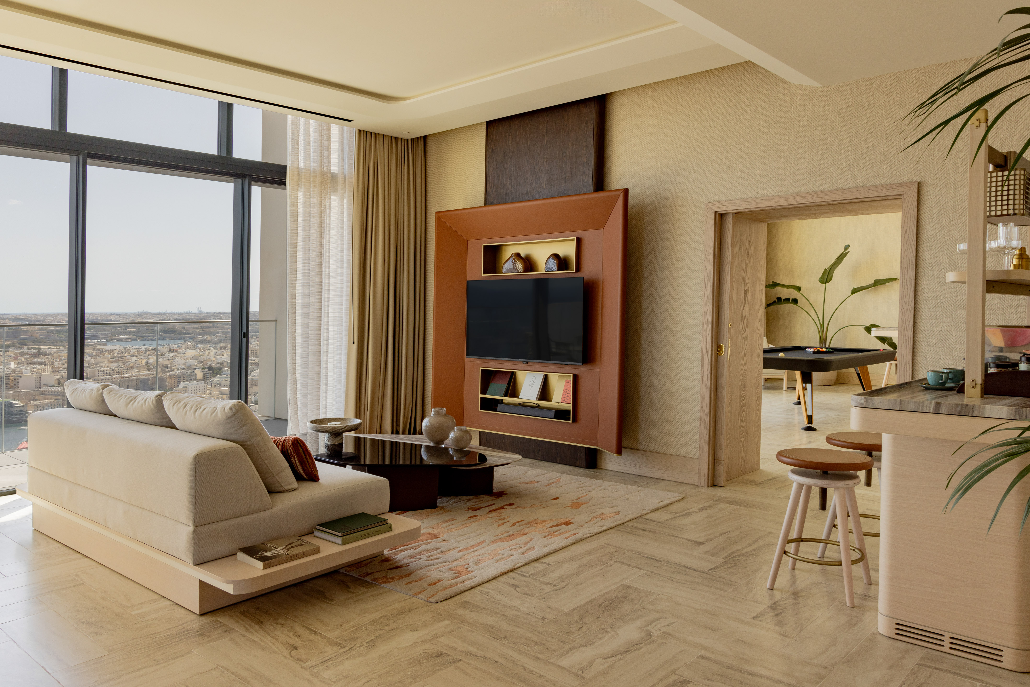 Modern elegant living room with city view, neutral sofa, TV, and billiards room.