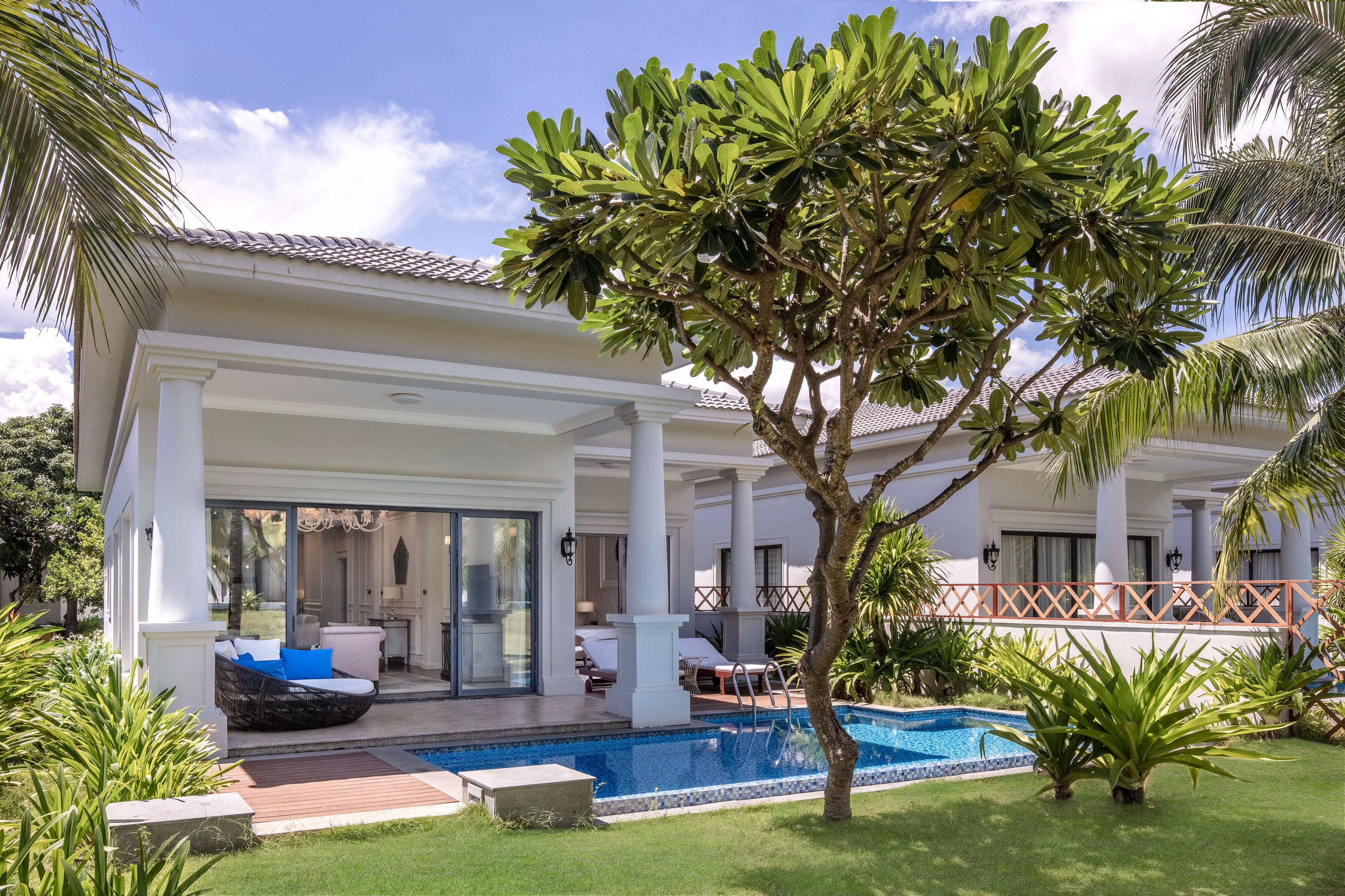 Luxury tropical villa with private pool, green lawn, and outdoor lounge.