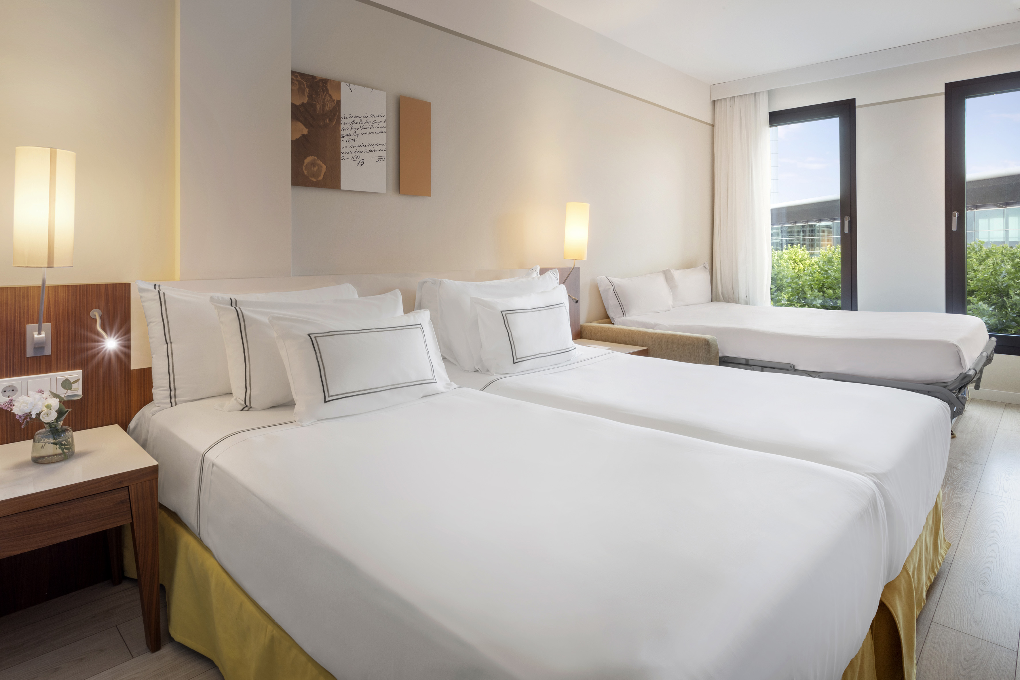 Hotel room with two twin beds, a pull-out sofa bed, and large windows.