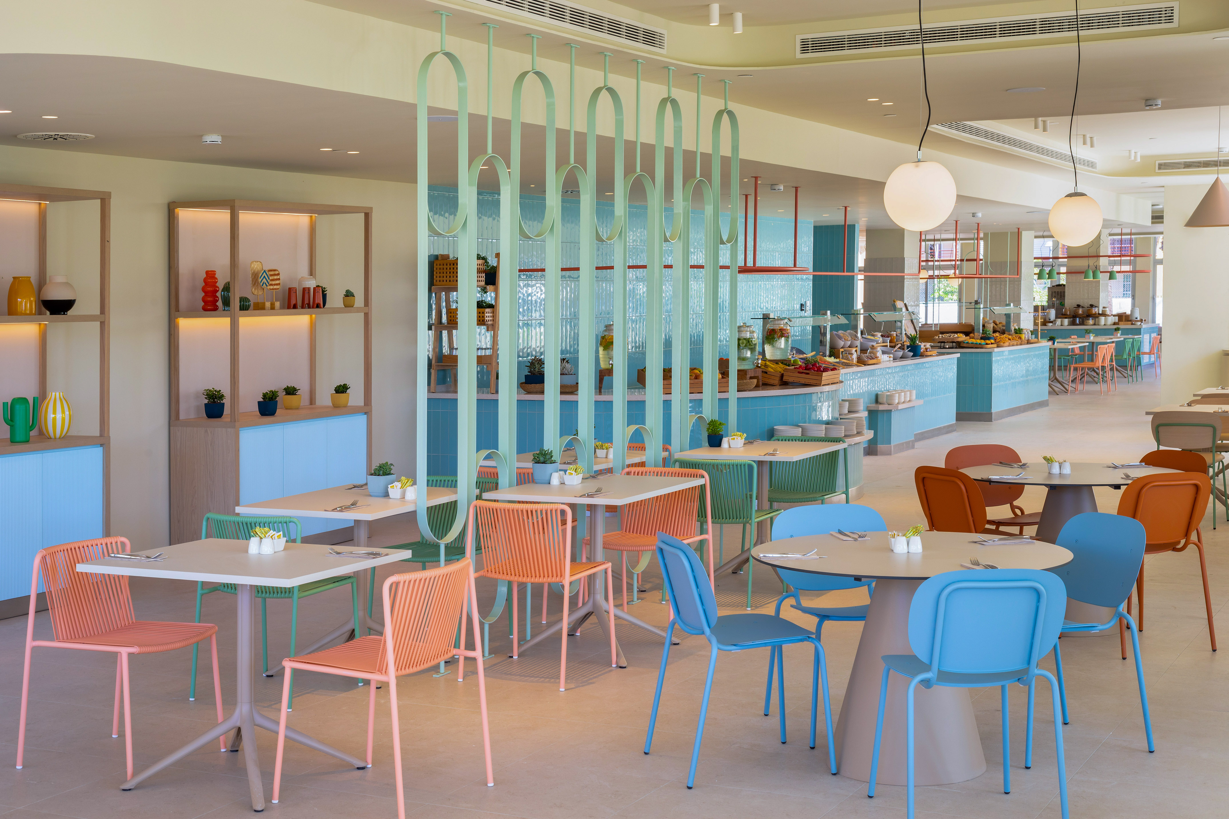 Colorful modern hotel restaurant buffet area with vibrant chairs and decor.