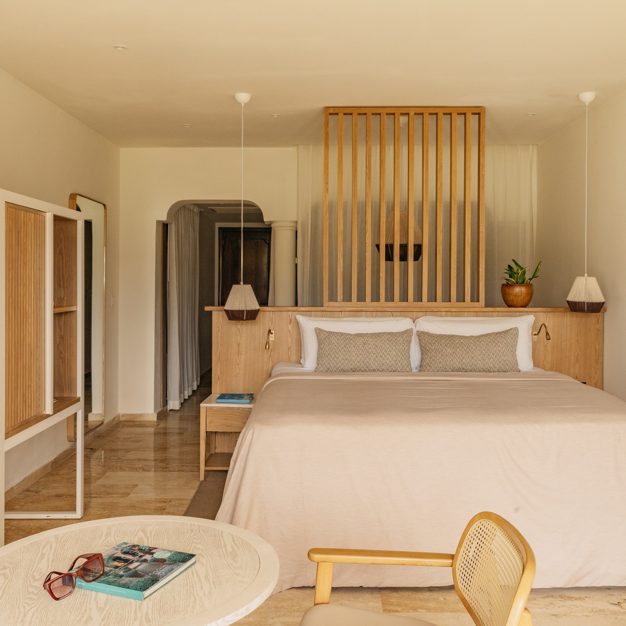 Bright hotel room with wooden slat headboard, king bed, and minimalist decor.