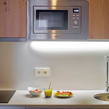 a microwave above a sink and a bowl of fruit