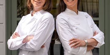 two women in white coats standing back to back with arms crossed