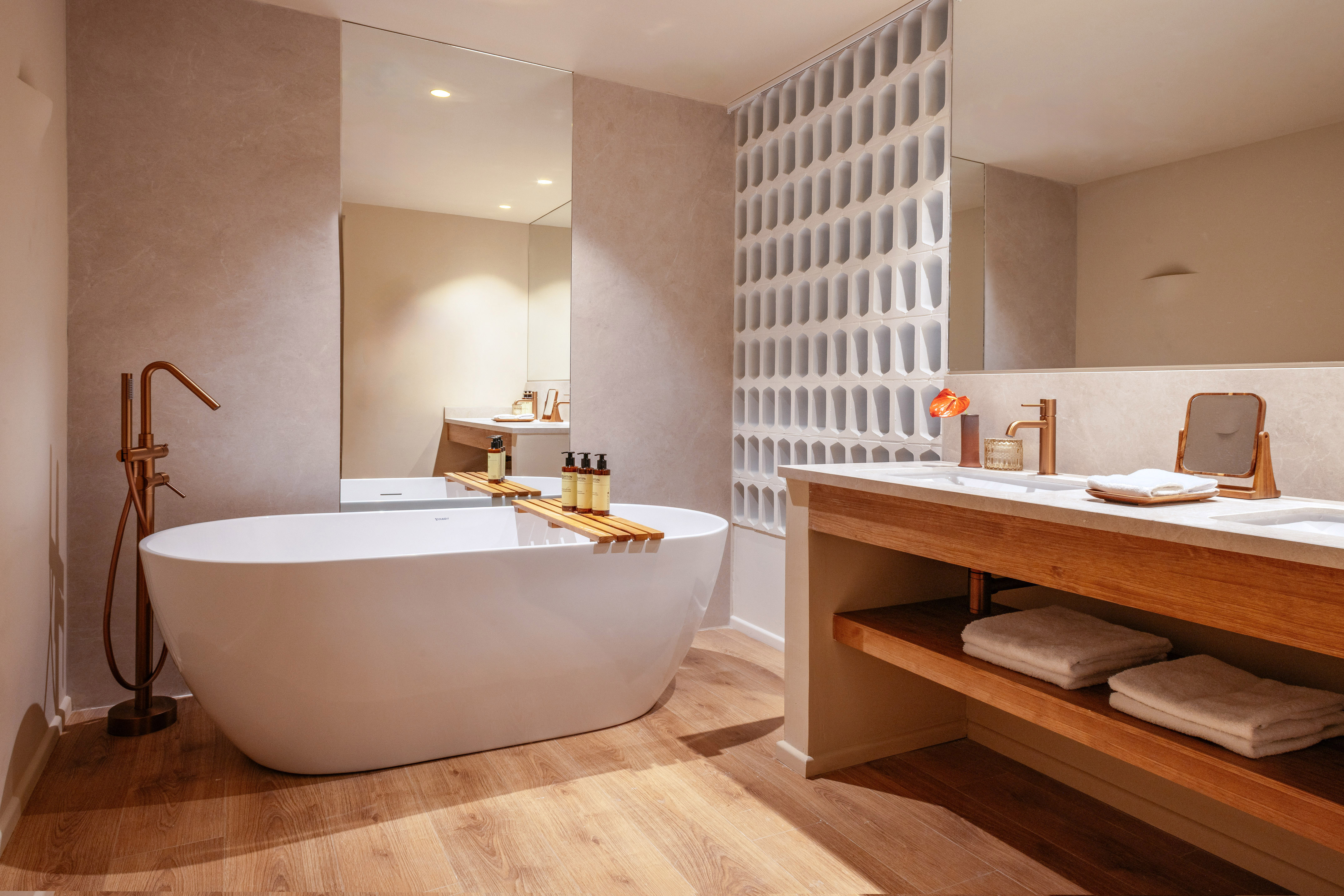 Modern bathroom with freestanding tub, wood vanity, and bronze fixtures.