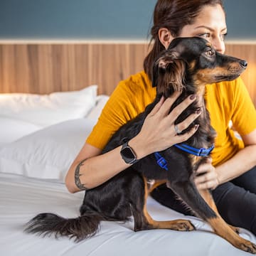 a woman sitting on a bed with a dog