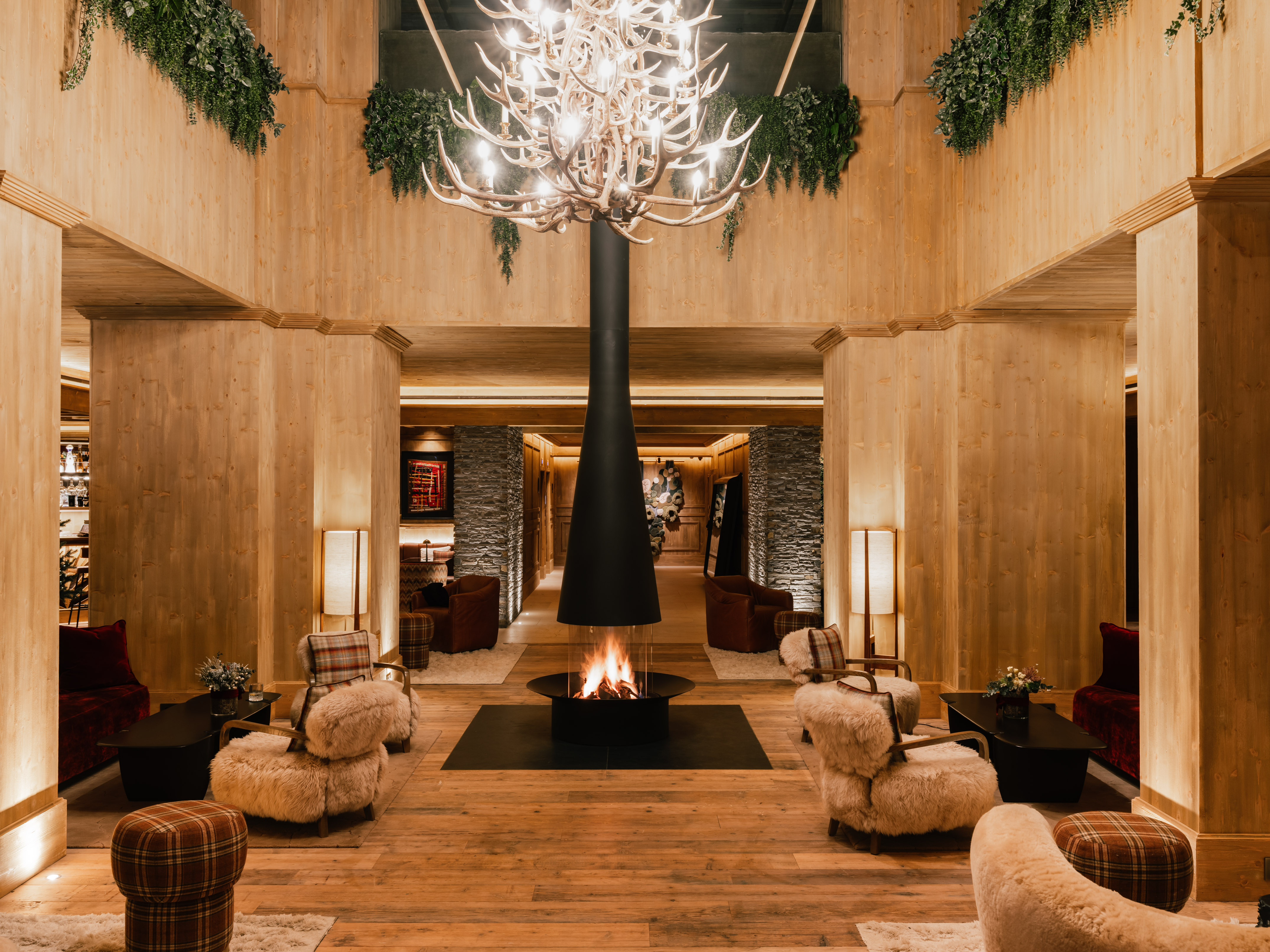 Lobby de hotel alpino con chimenea central, madera y candelabro de astas. - MiM Baqueira Meliá Collection, باكويرا بيريت